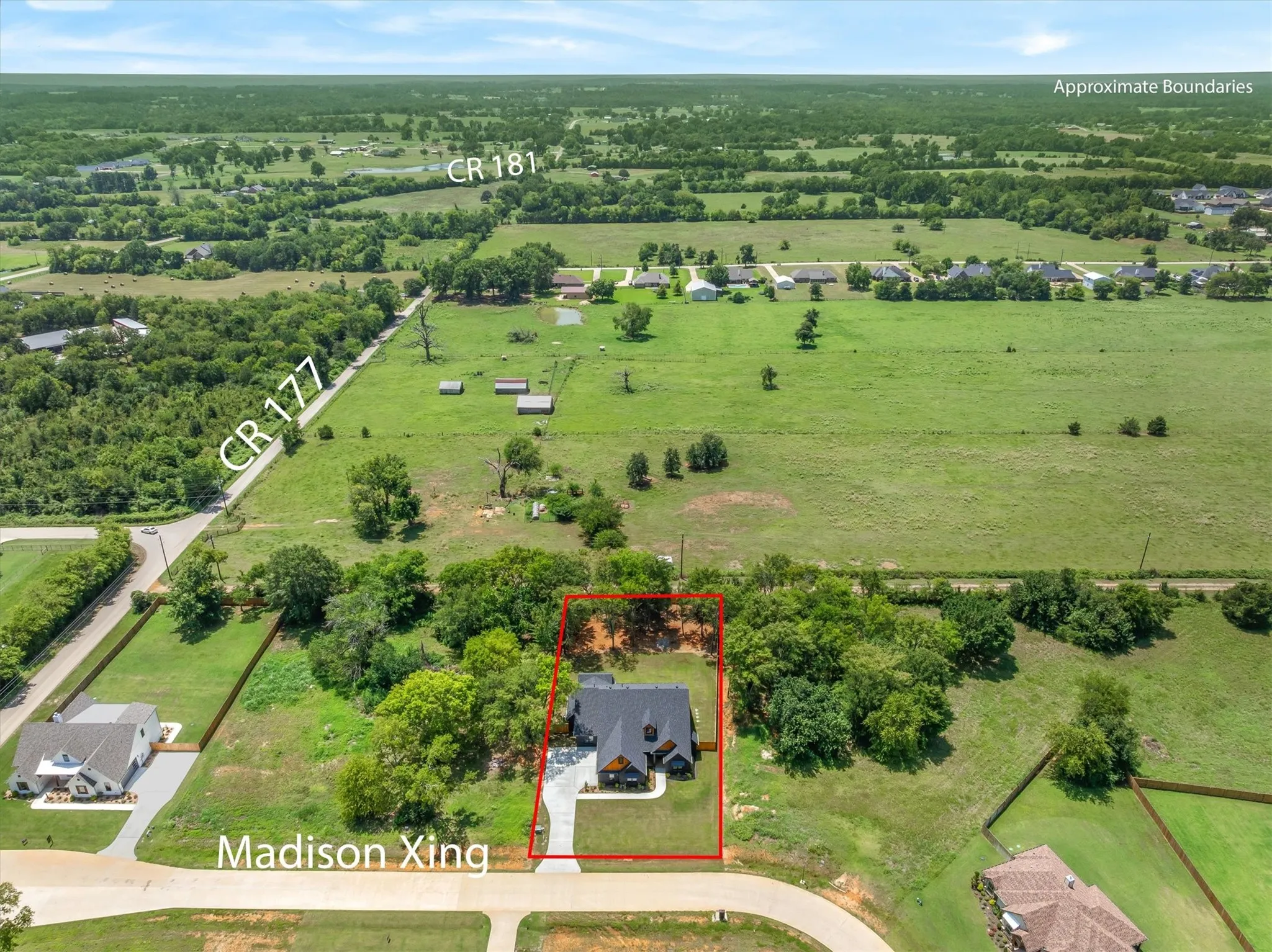 Aerial perspective showcasing a property outlined in red, featuring a single-story residence with a dark roof and light-colored driveway
