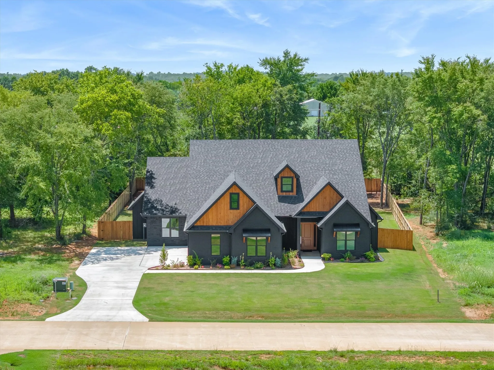 Modern dark exterior featuring wood-finish gables, a dark shingle roof, and a concrete driveway
