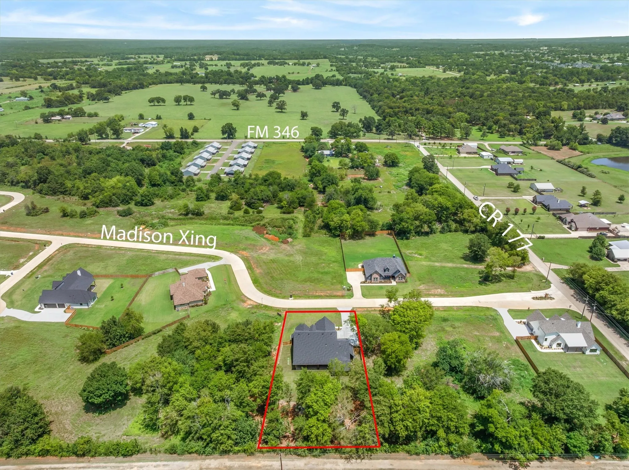 Aerial perspective showcasing a property outlined in red, featuring a dark-roofed residence nestled among mature trees