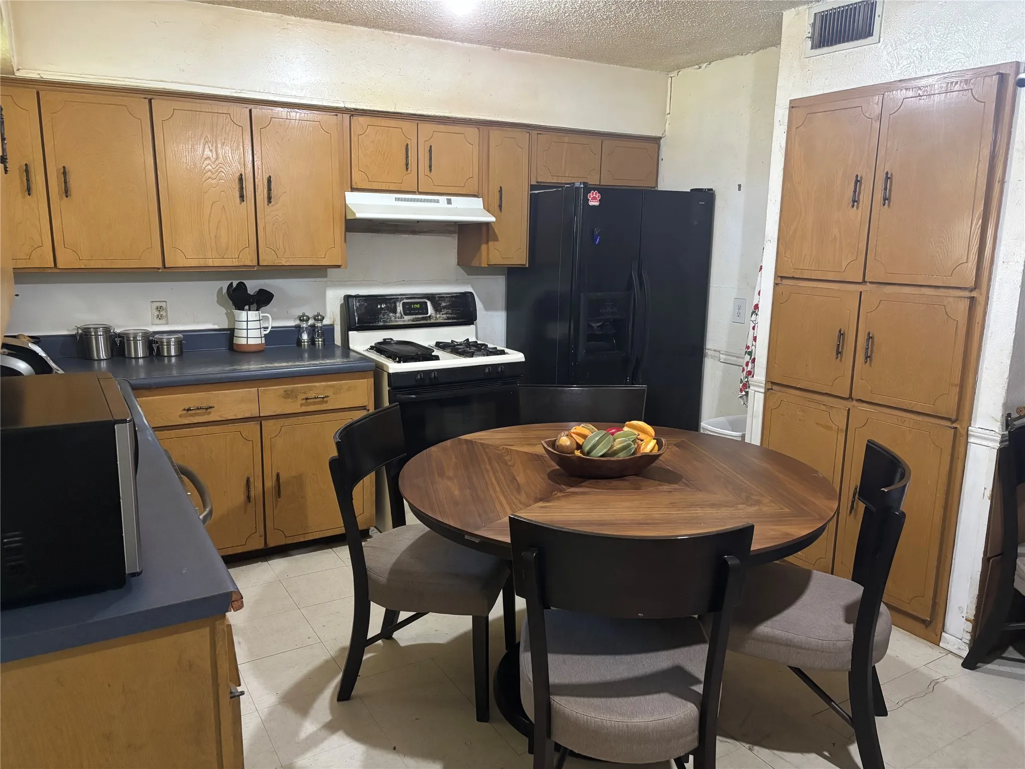 Kitchen featuring wood-finish cabinetry, a freestanding range, a black refrigerator, and a built-in pantry