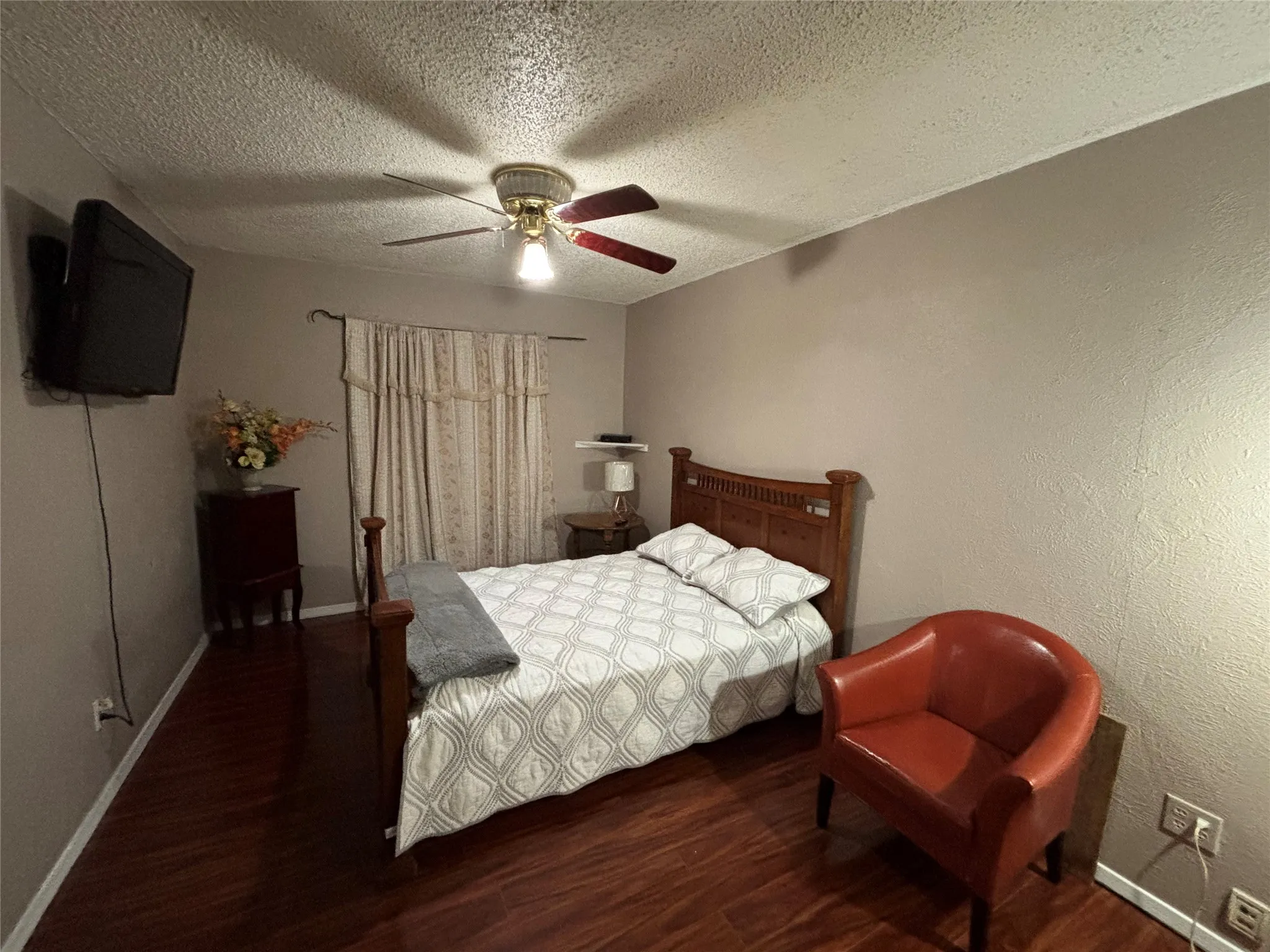 Master bedroom featuring wood-finish flooring, neutral wall paint, and a ceiling fan with light fixture