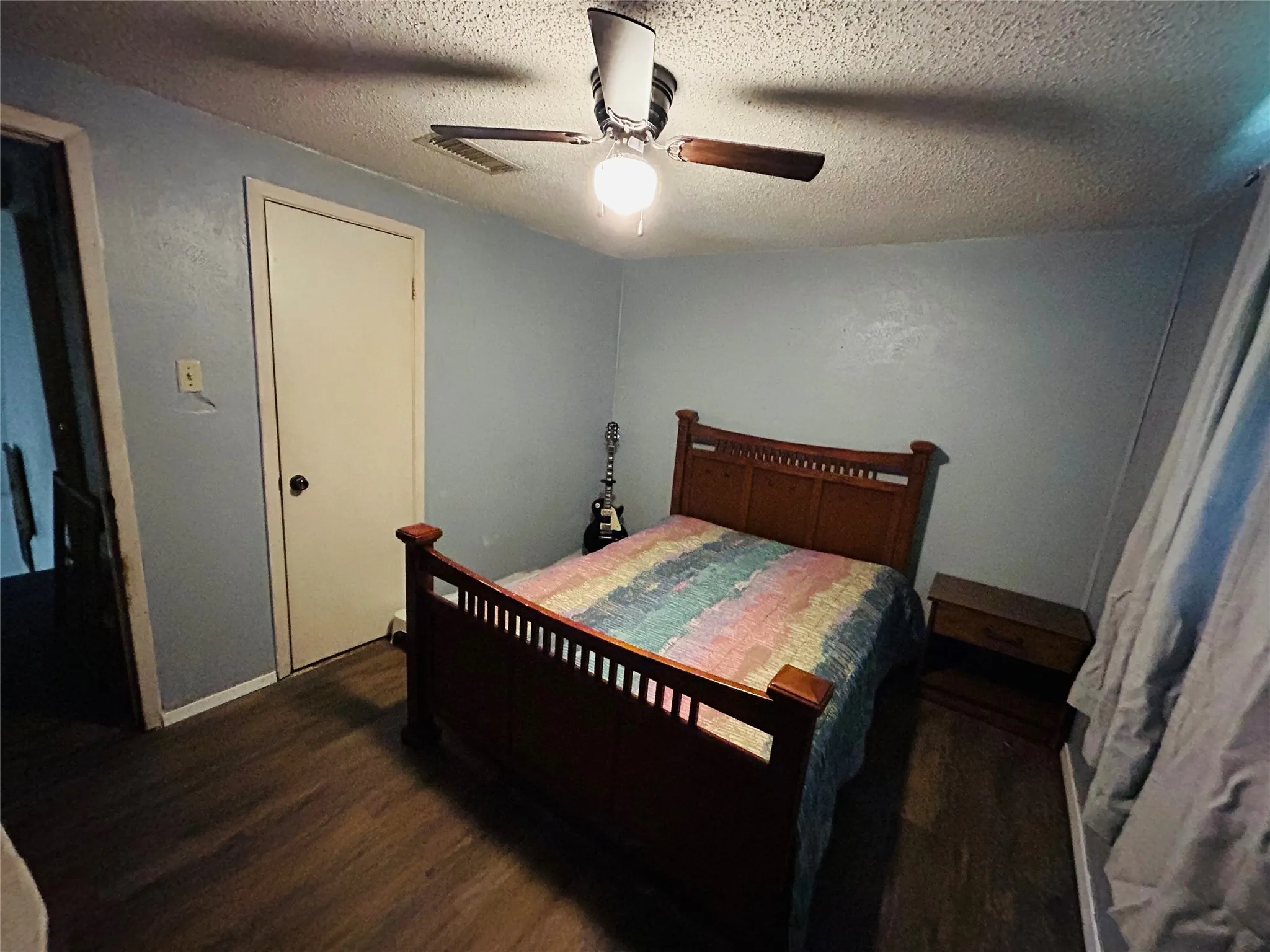 Blue bedroom featuring wood-finish flooring, light blue wall paint, and a ceiling fan with integrated lighting