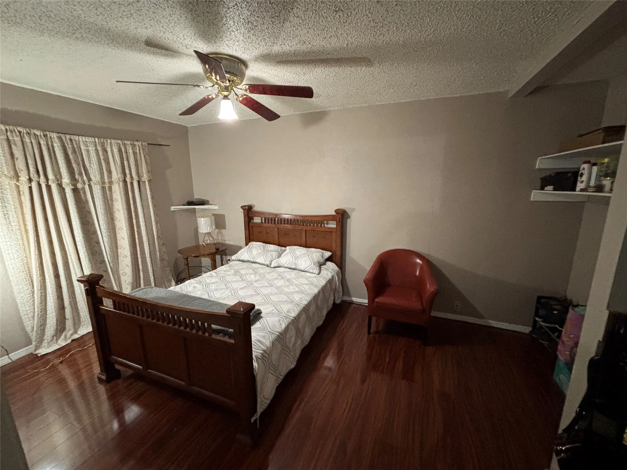 Master bedroom featuring wood-finish flooring, a ceiling fan with light fixture, and neutral wall tones