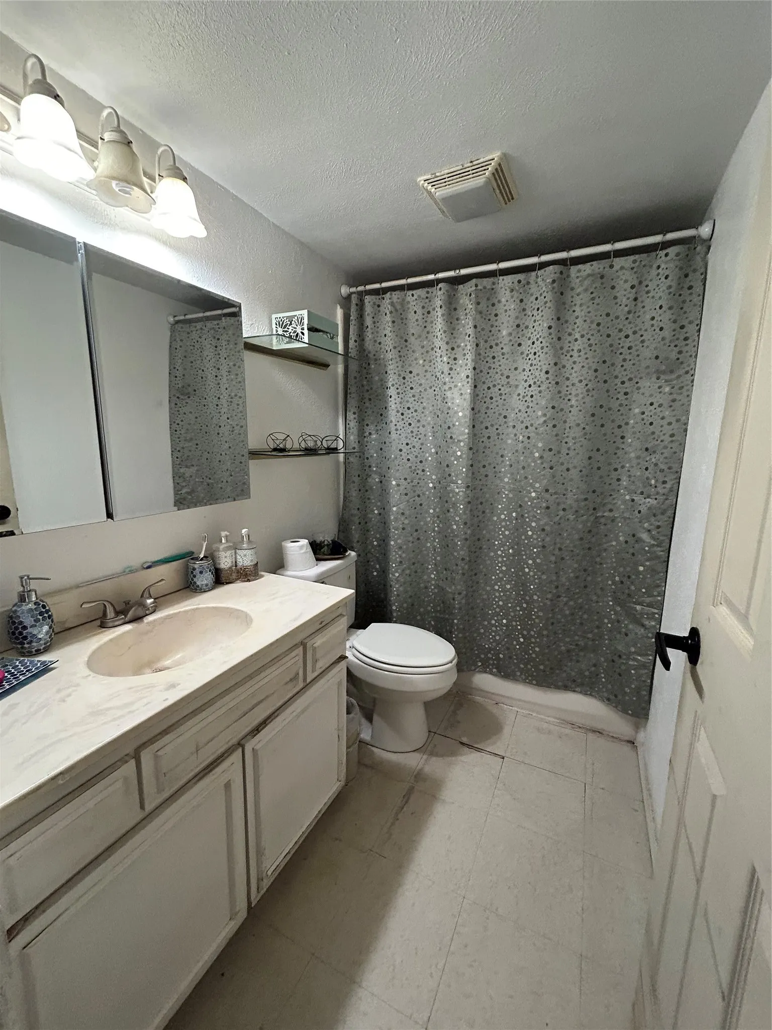 Bathroom featuring a built-in vanity with an integrated sink and light-toned countertop, and a shower area.