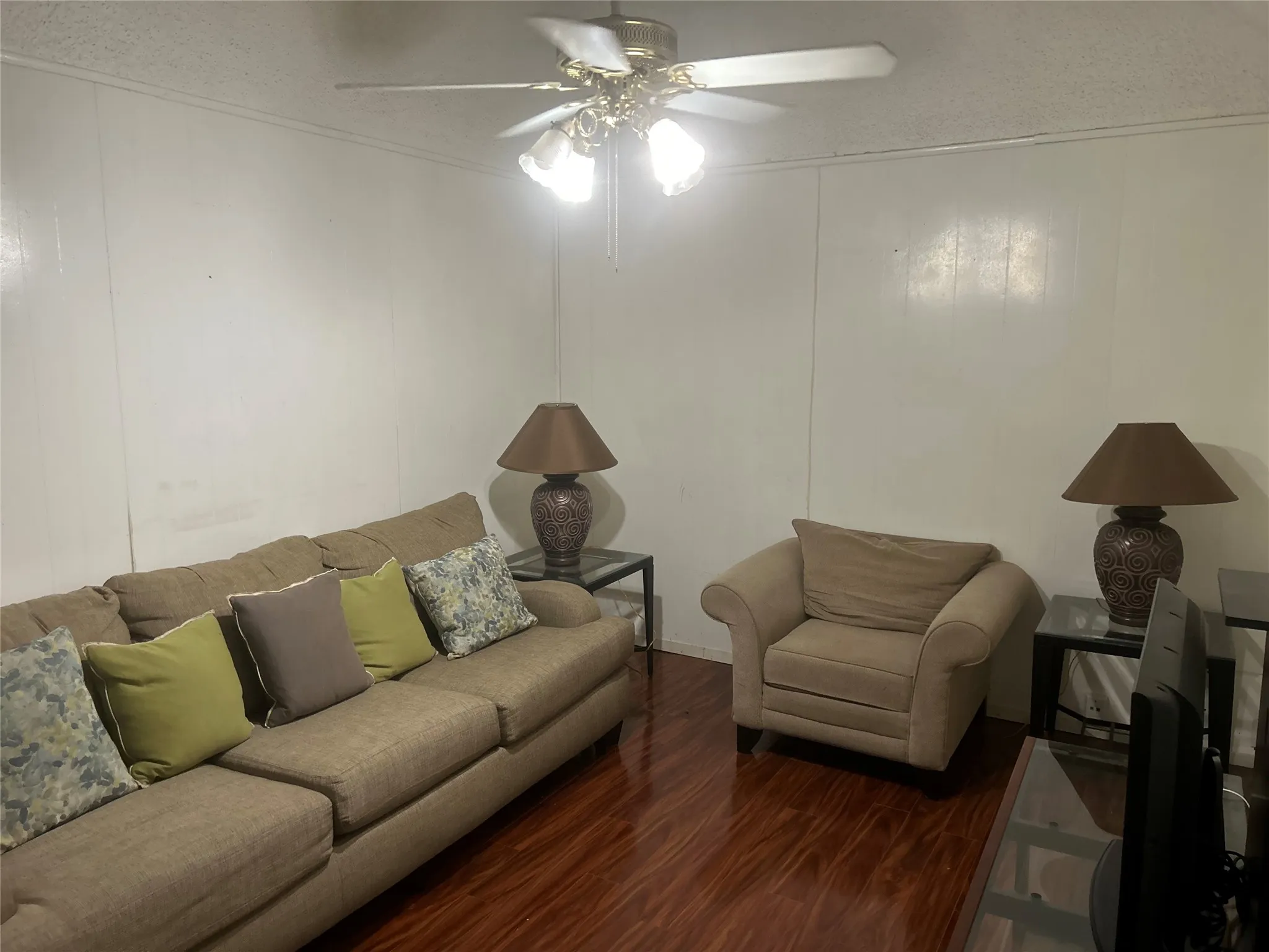 Hardwood-finish flooring, white paneled walls, and a ceiling fan with integrated lighting
