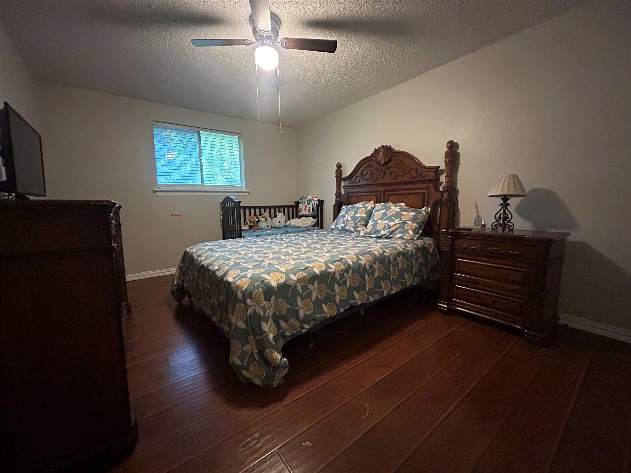 Bedroom featuring wood-finish flooring, a window with horizontal blinds, and a ceiling fan with integrated lighting
