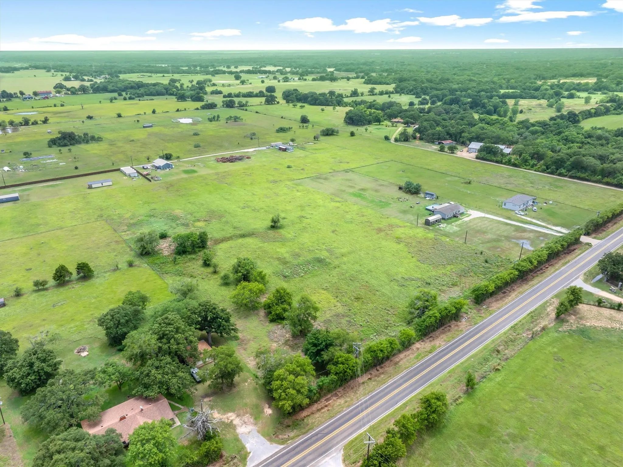 Expansive green landscape featuring scattered trees and multiple structures