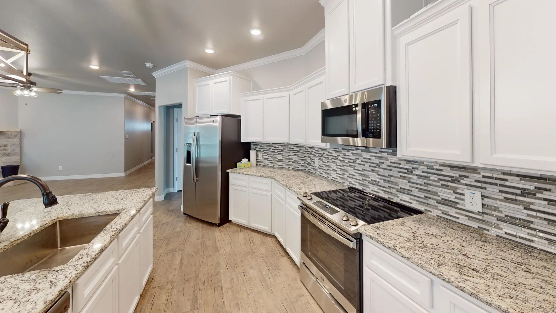 Kitchen with white shaker cabinetry, speckled countertops, and a mosaic tile backsplash