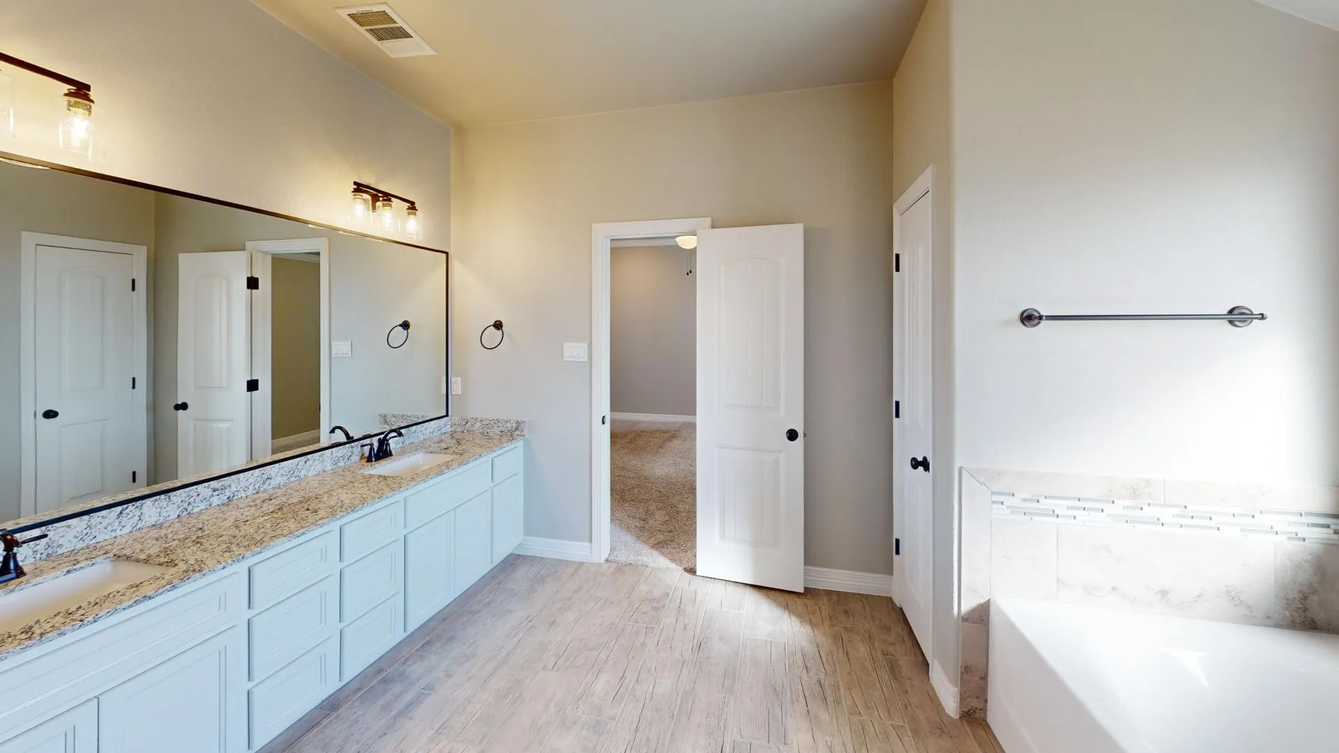 Dual vanity featuring white cabinetry, light-toned granite countertops, and undermount sinks