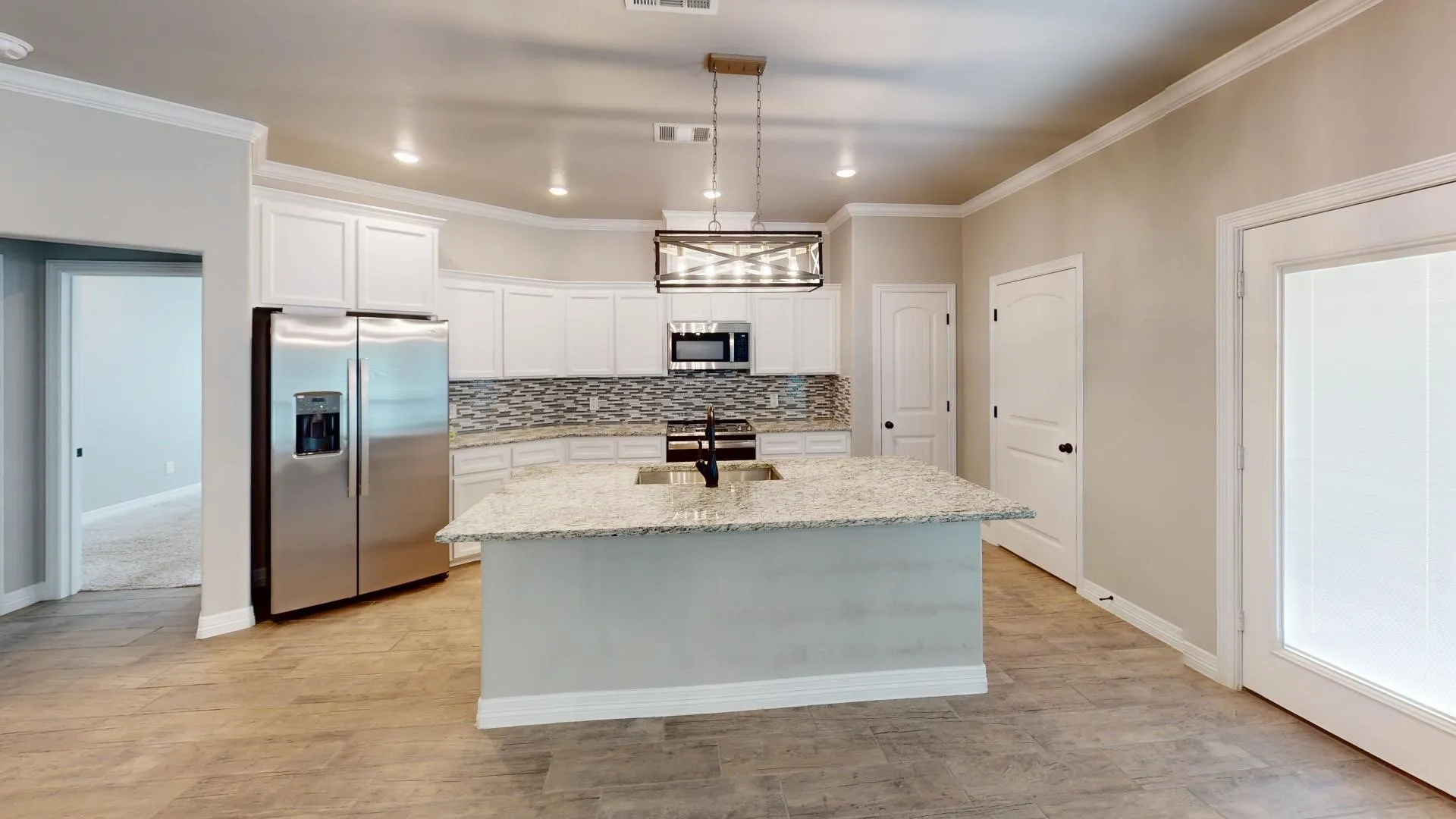 Open-concept kitchen featuring an island with an undermount sink, stainless steel appliances, white cabinetry, a tiled backsplash, and wood-look flooring