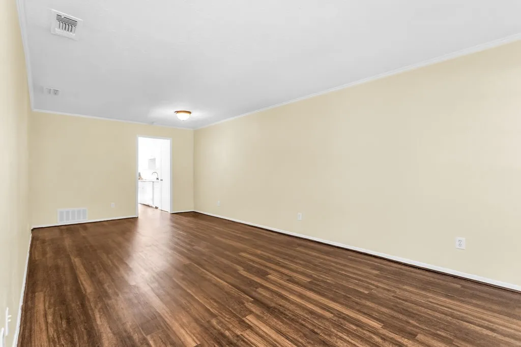 Spacious interior room featuring wood-finish flooring, light-toned walls, and white trim