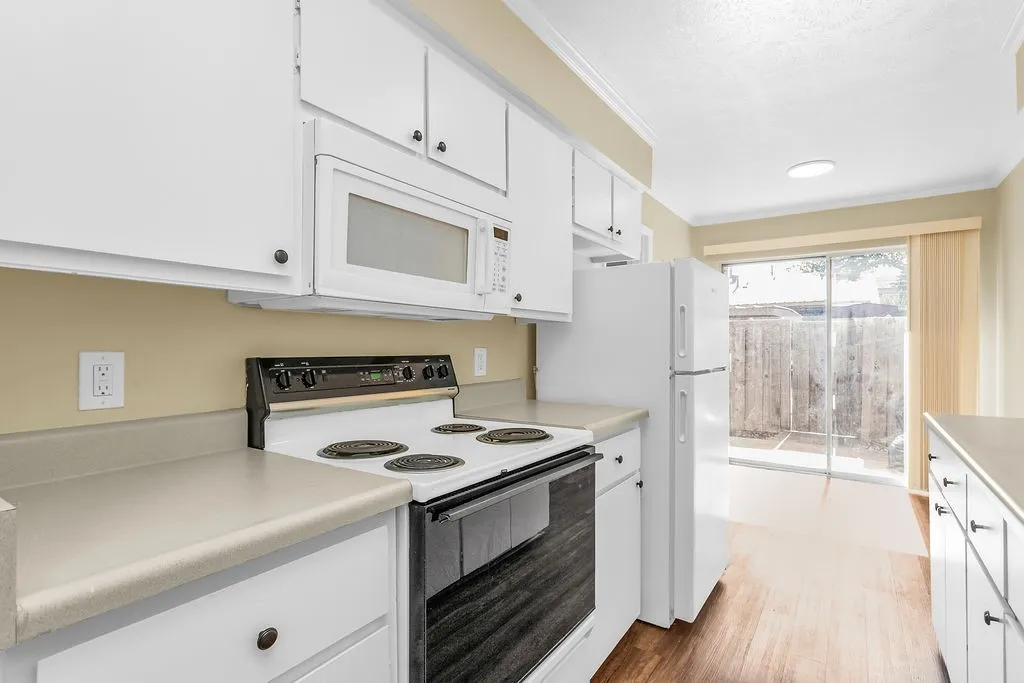 Kitchen featuring white cabinetry, light-toned countertops, and wood-finish flooring