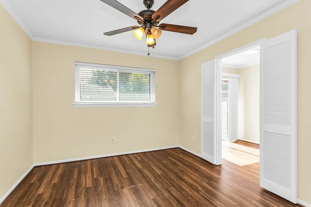 Bedroom #3 which was shown as an office in virtual staging.  Room featuring wood-finish flooring, a window with horizontal blinds, and a ceiling fan with integrated lighting