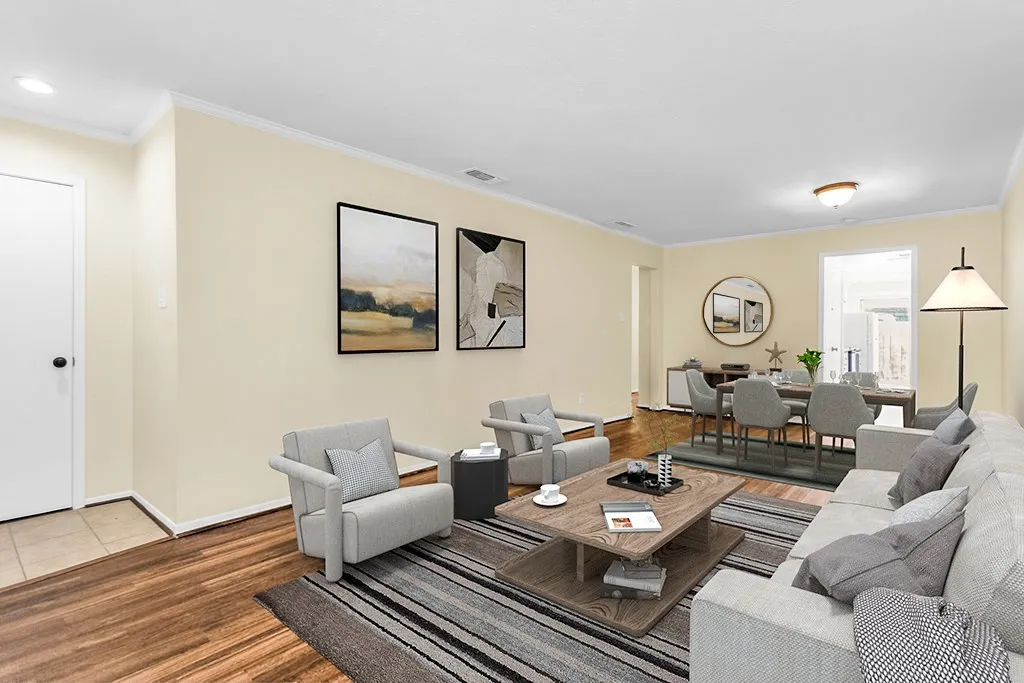 Virtually staged Spacious living area featuring wood-finish flooring, light-toned walls, and white crown molding
