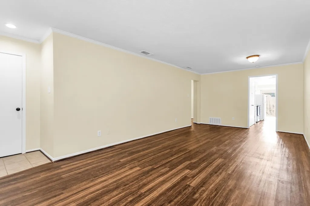Spacious room featuring wood-finish flooring, light-toned walls, and white trim