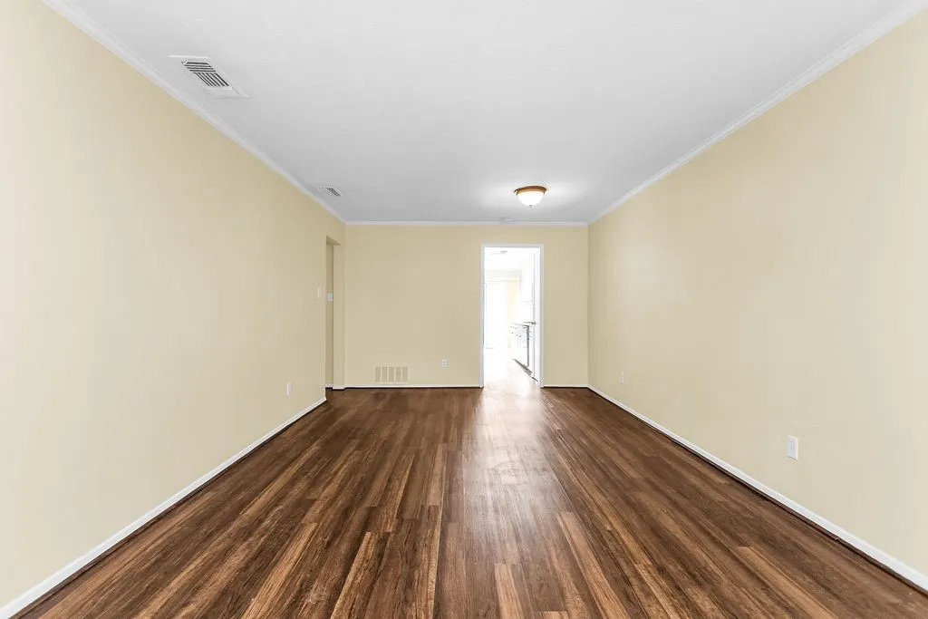 Spacious interior with wood-finish flooring, light-toned walls, and white crown molding