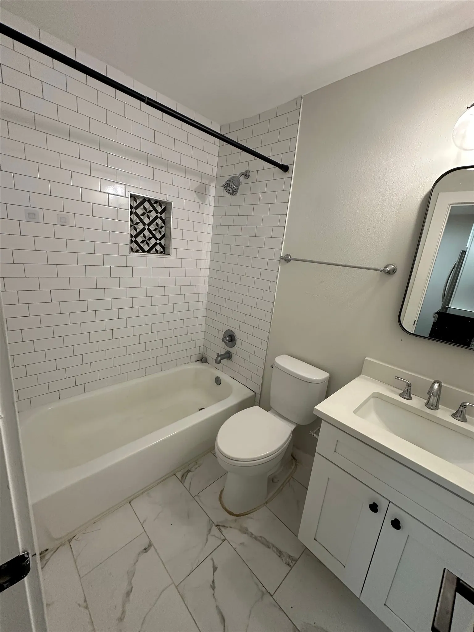 Bathroom featuring a white subway tile shower surround with a decorative tile niche