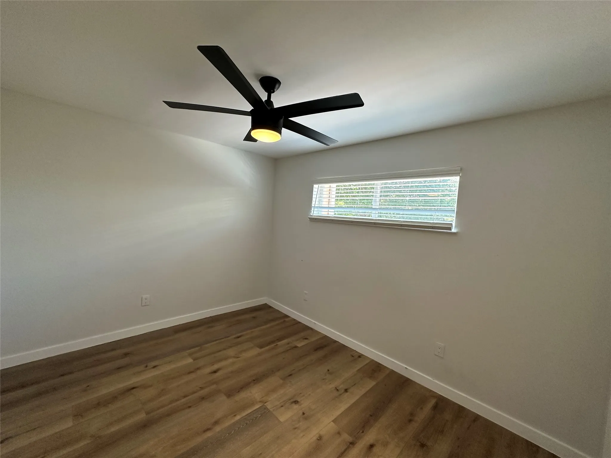 Room featuring wood-finish flooring, white baseboards, and neutral wall tones