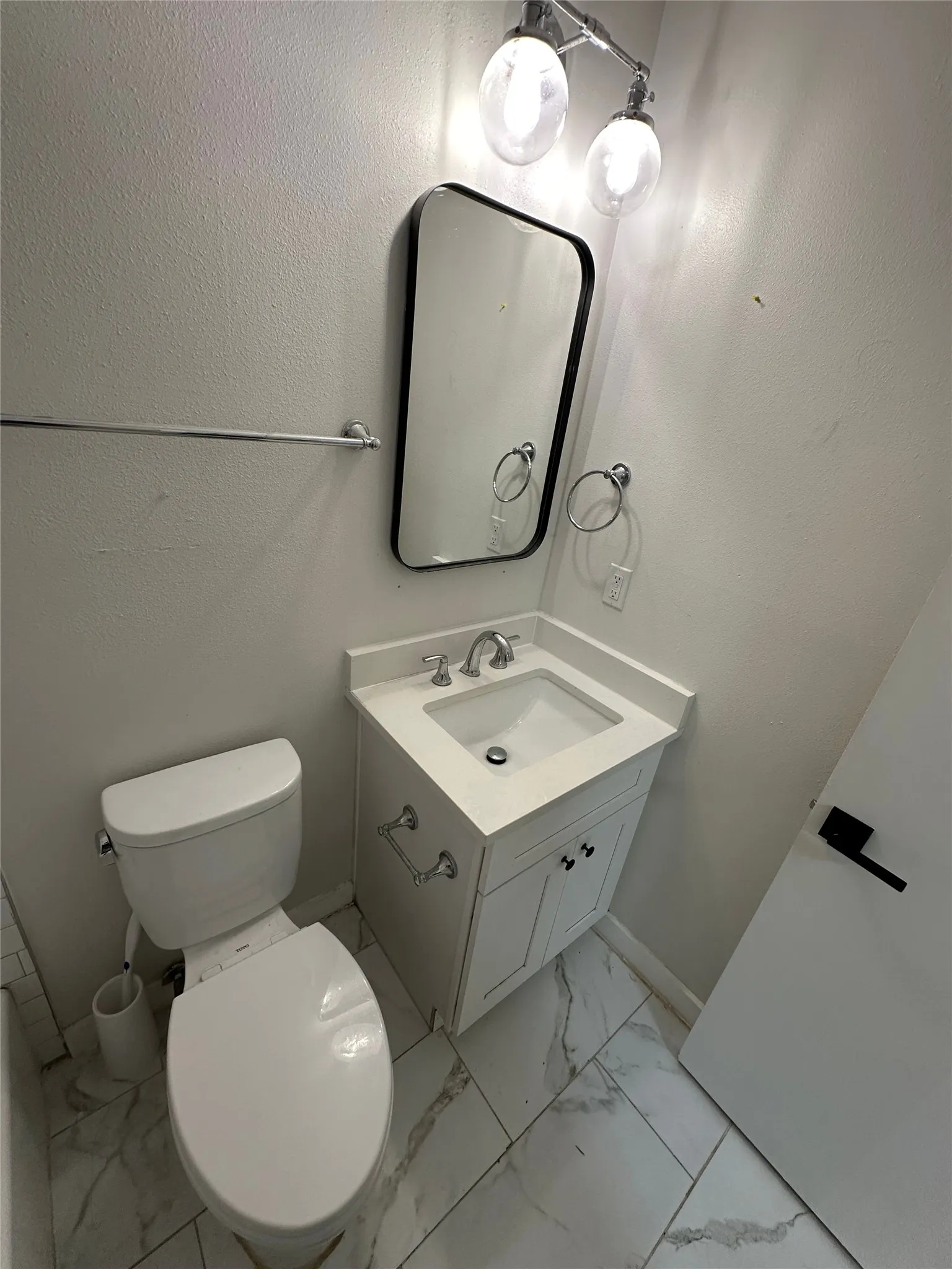Bathroom featuring a white vanity with a recessed sink, brushed nickel faucet, and a quartz-finish countertop