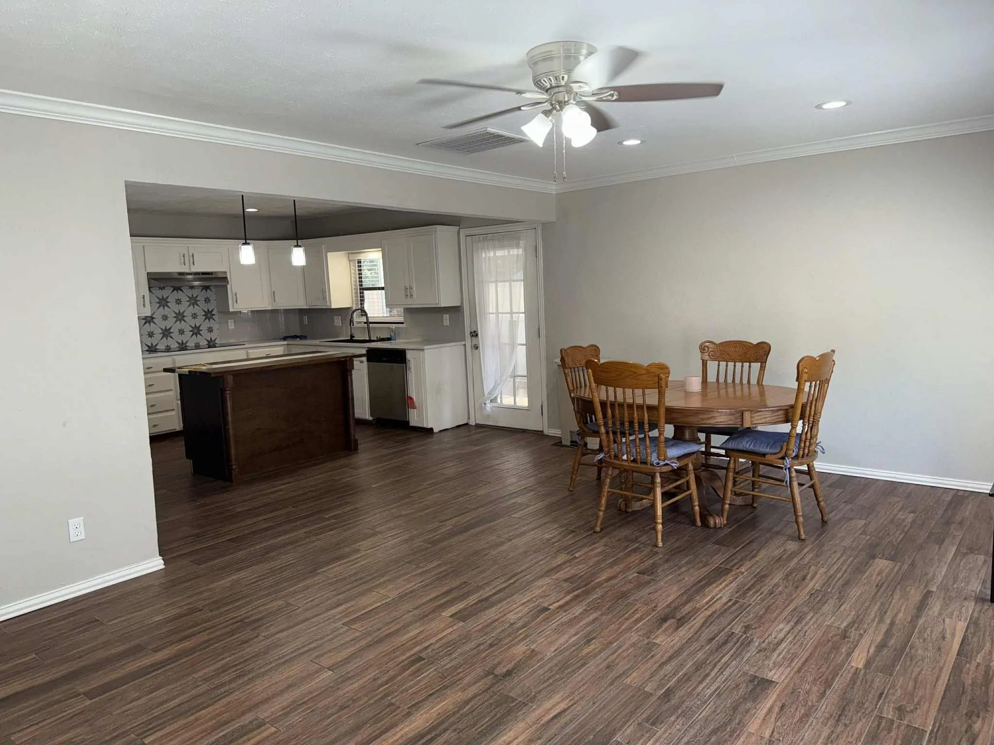 Open-concept living area featuring wood-finish flooring, recessed lighting, and crown molding