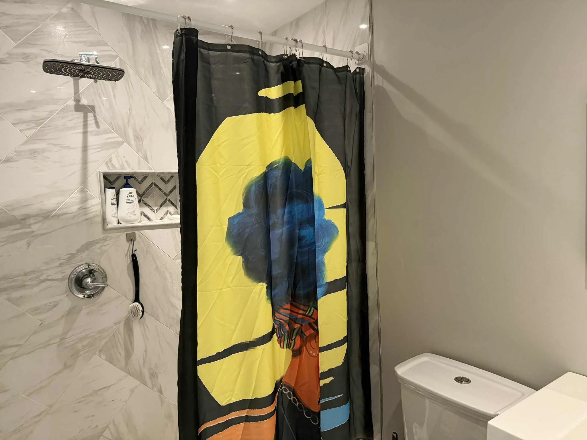 Shower featuring large format tile in a herringbone pattern, rain shower head, recessed shower niche with decorative tile inlay, and polished chrome fixtures