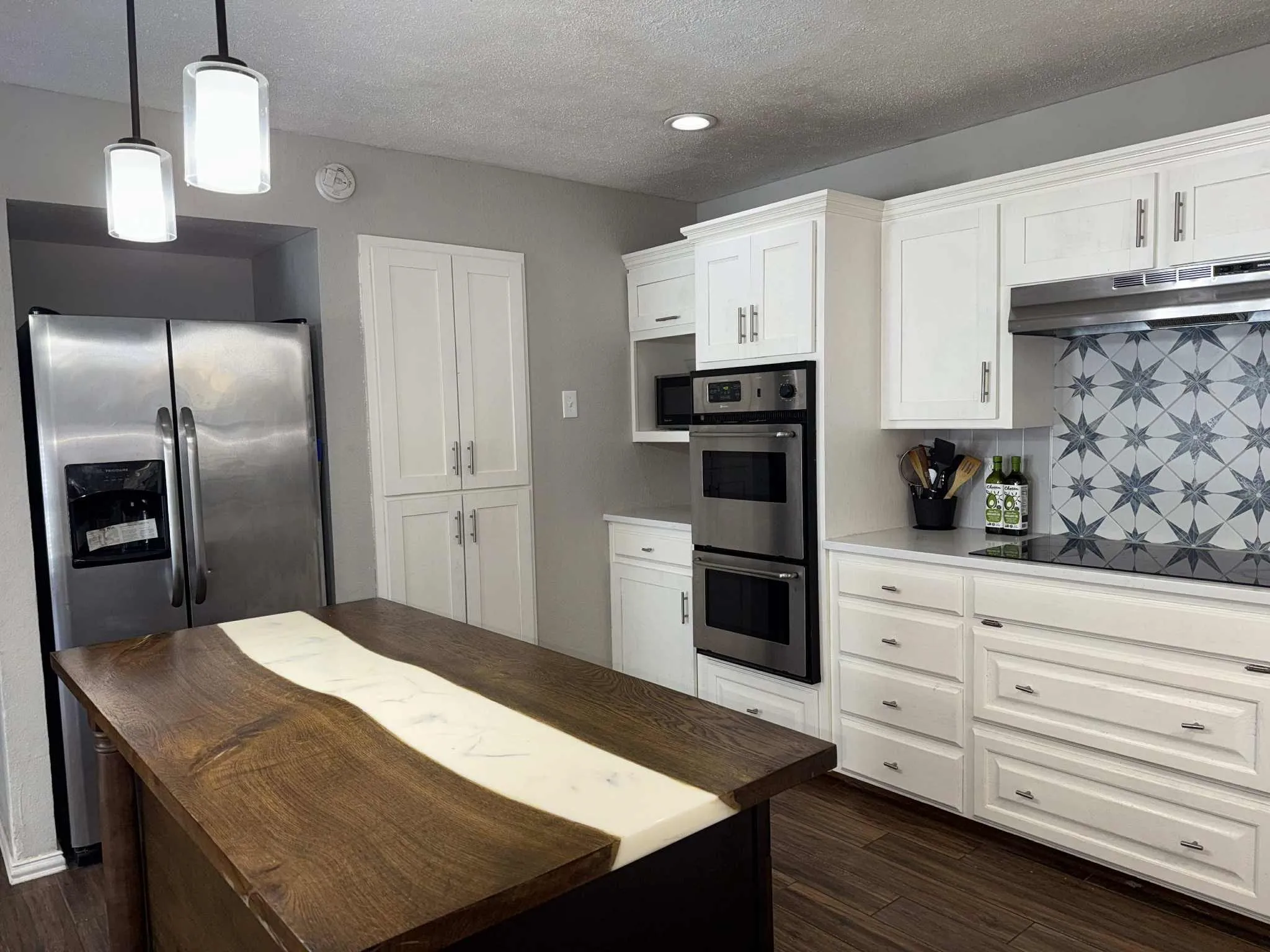 Kitchen featuring a wood-finish island with a resin inlay, white shaker-style cabinetry, and stainless steel appliances