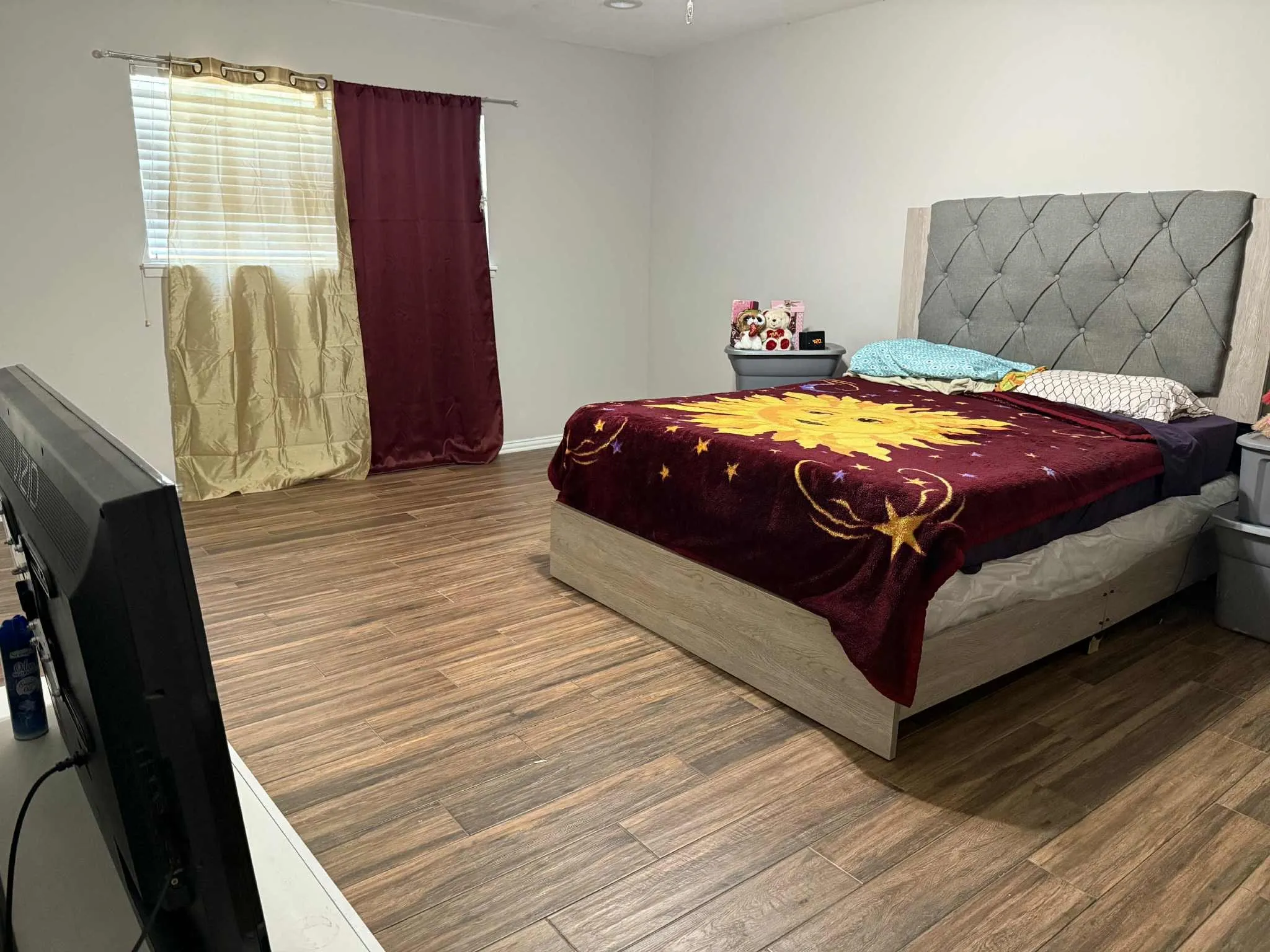 Bedroom featuring wood-finish flooring, a window with horizontal blinds, and neutral painted walls