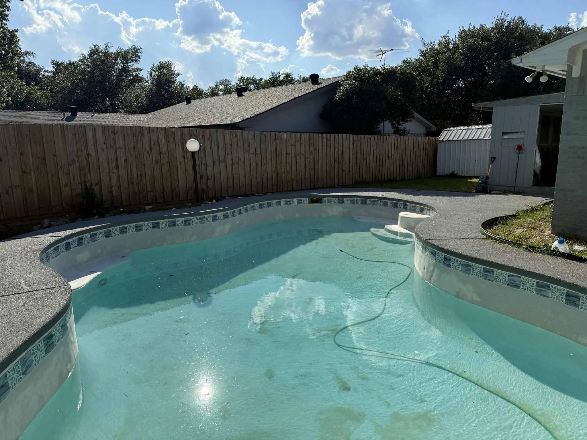 Freeform swimming pool featuring integrated steps and a textured concrete deck