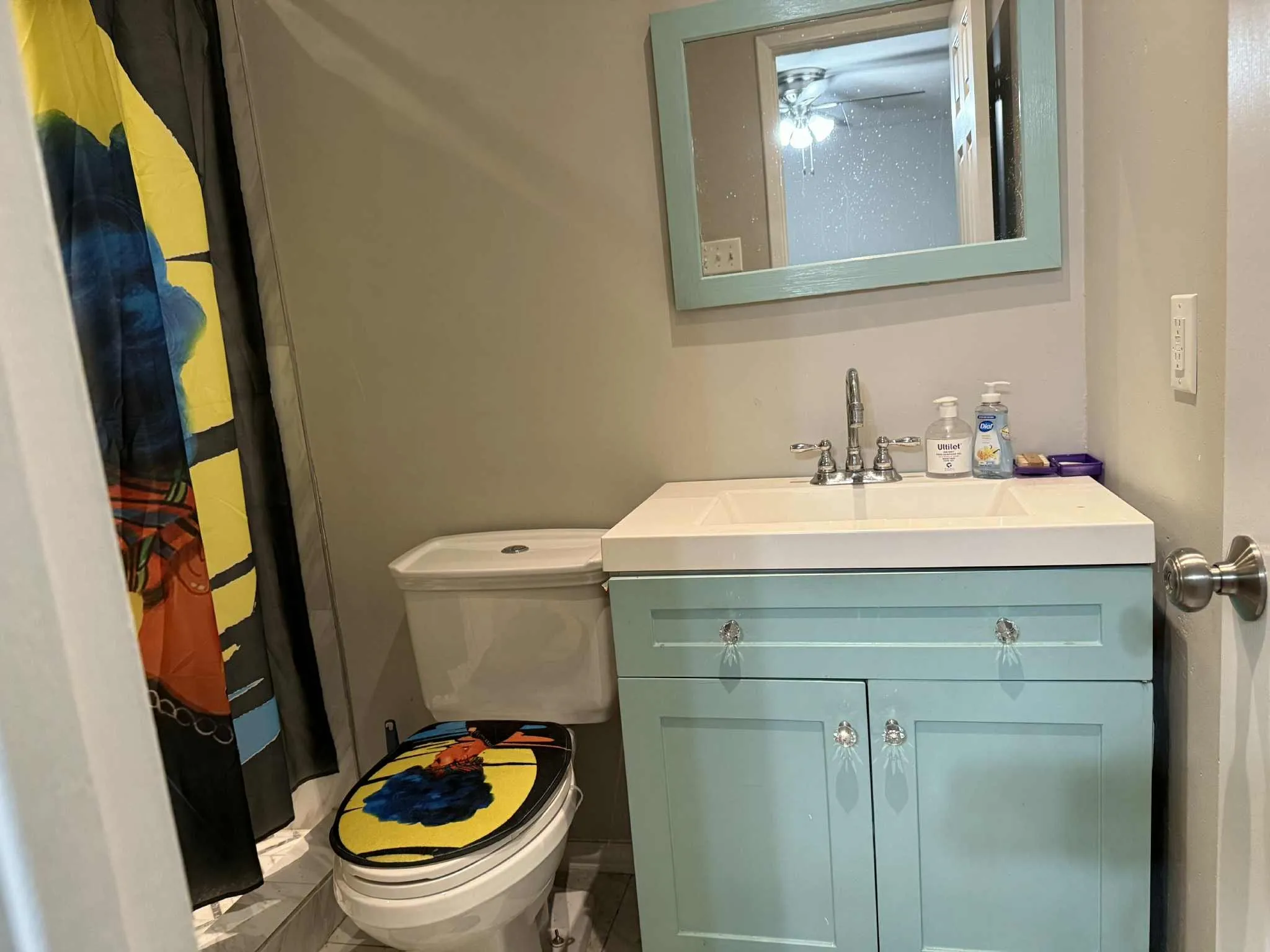 Bathroom vanity featuring a light blue cabinet with crystal knobs, an integrated sink, and a framed mirror