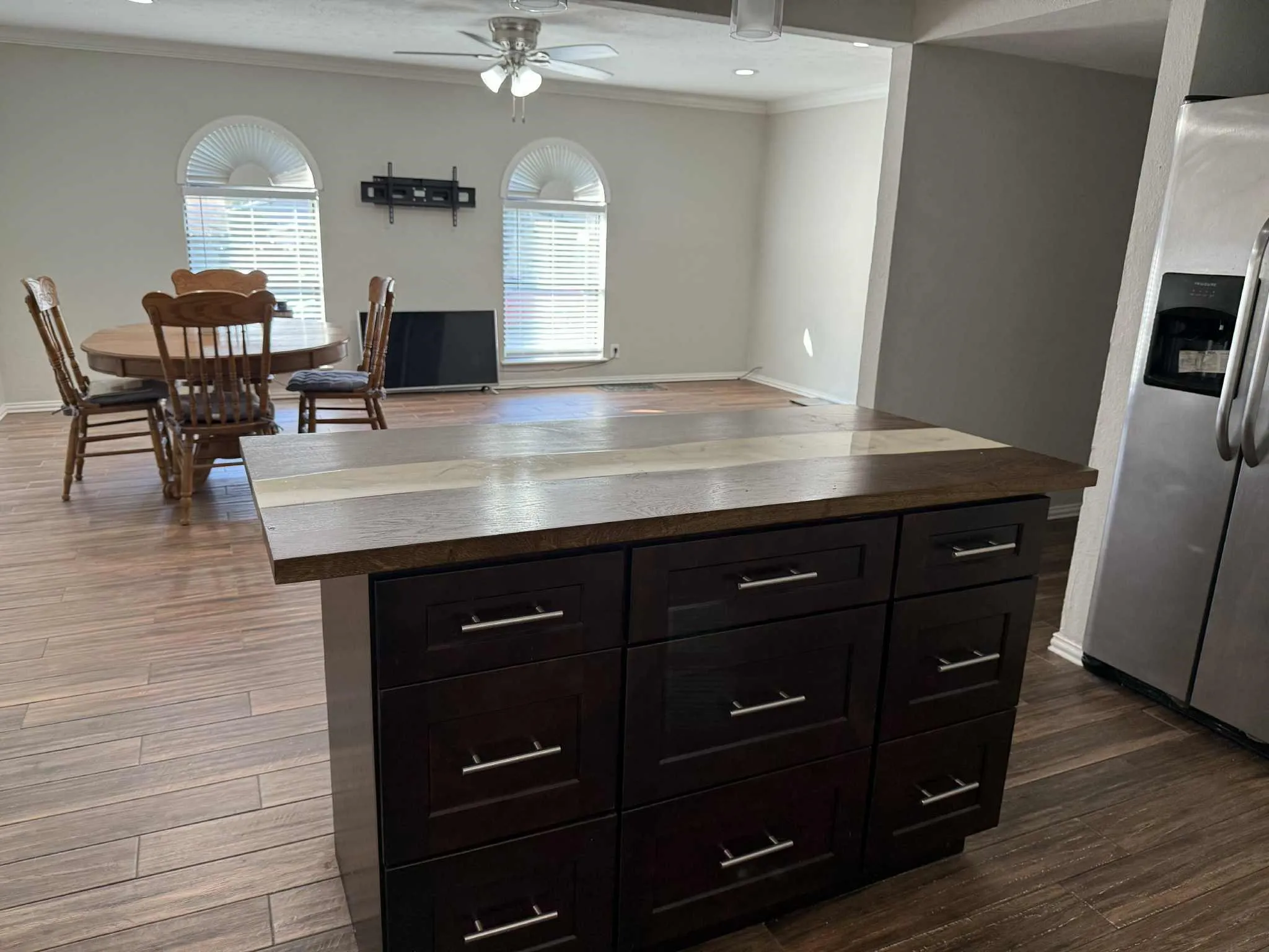 Kitchen island with dark wood cabinetry, brushed nickel hardware, and a multi-tone wood-finish countertop