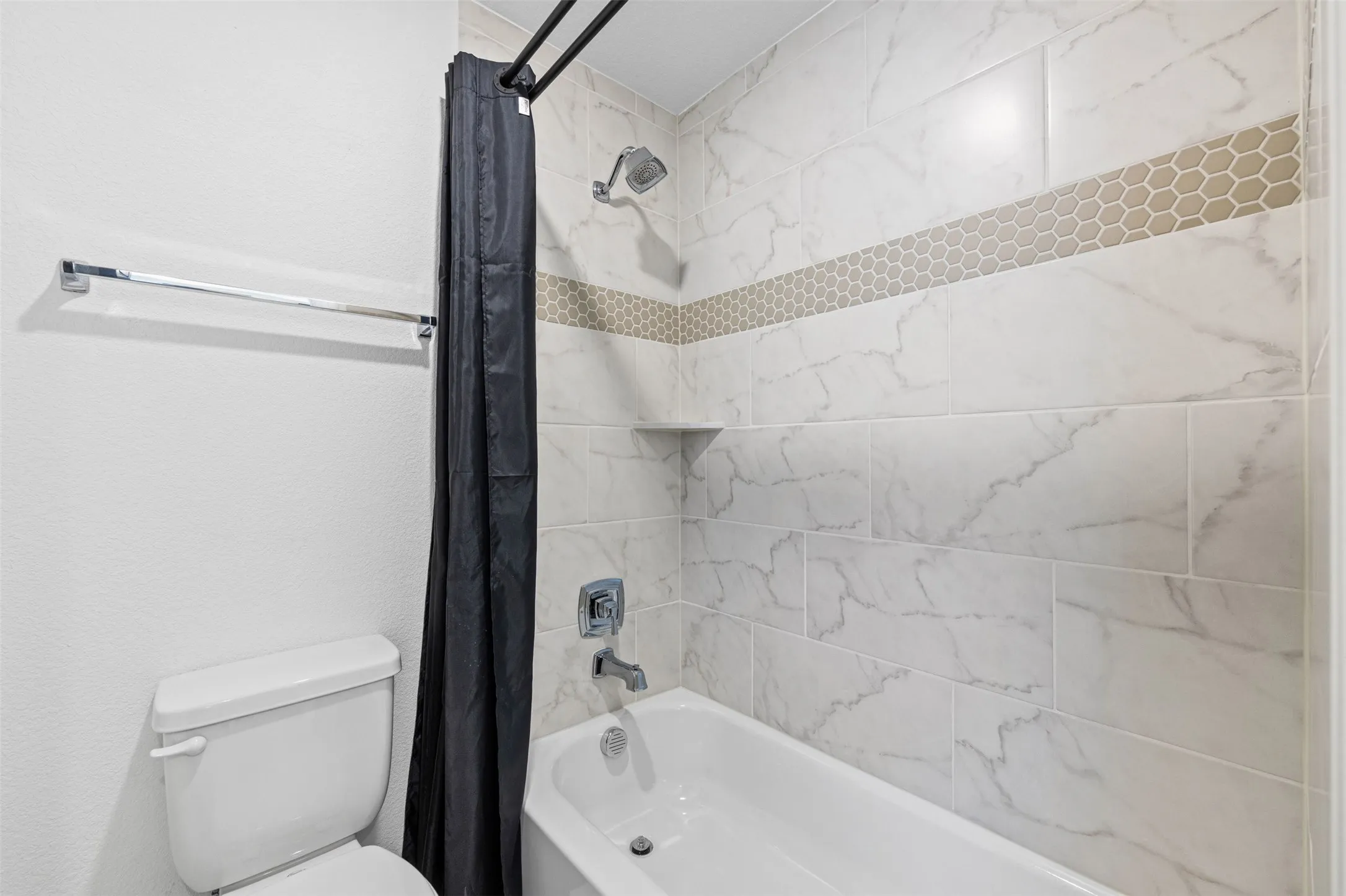 2nd Story Bathtub with shower fixture, white subway tile surround, honeycomb mosaic accent tile, and recessed shower shelf
