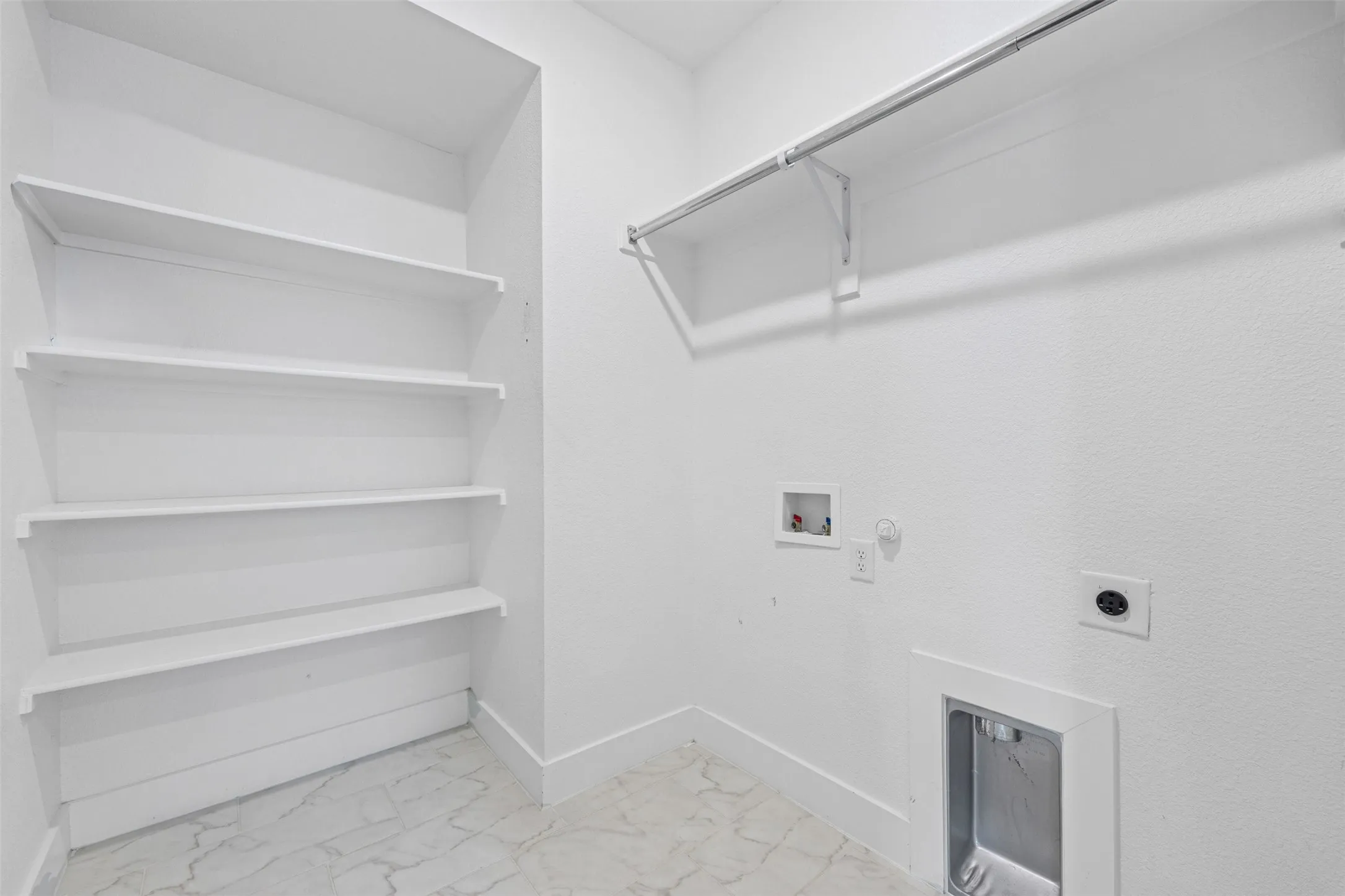 1st floor Laundry area with built-in shelving, white walls, and light-colored flooring