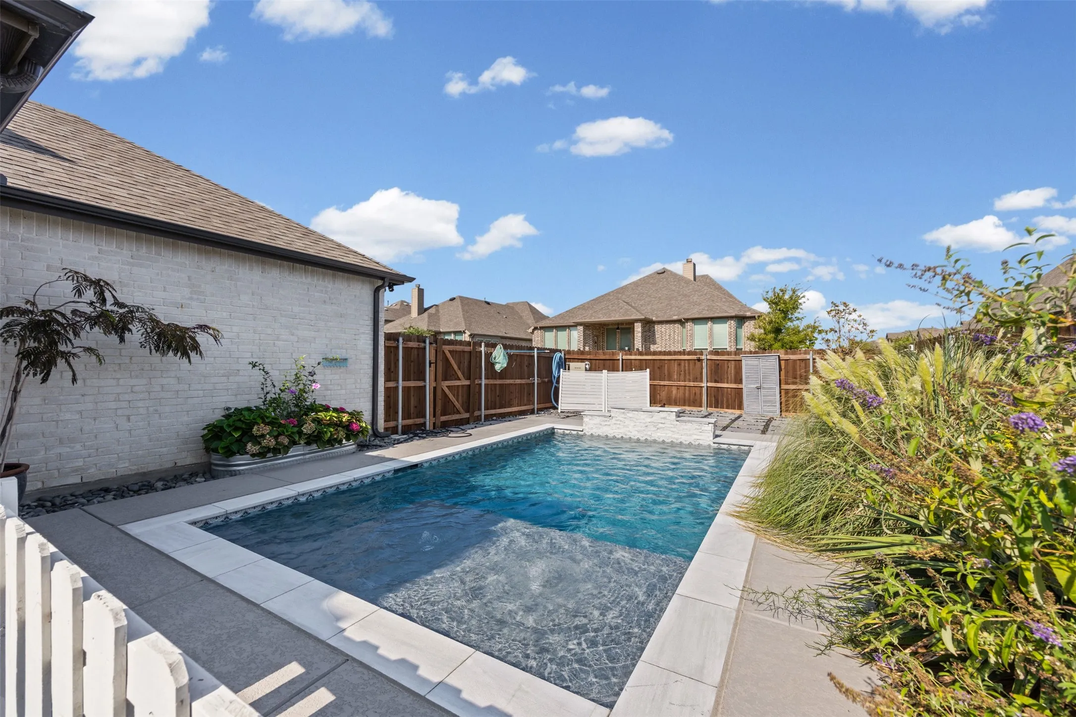 In-ground swimming pool with light-colored coping, surrounded by concrete decking
