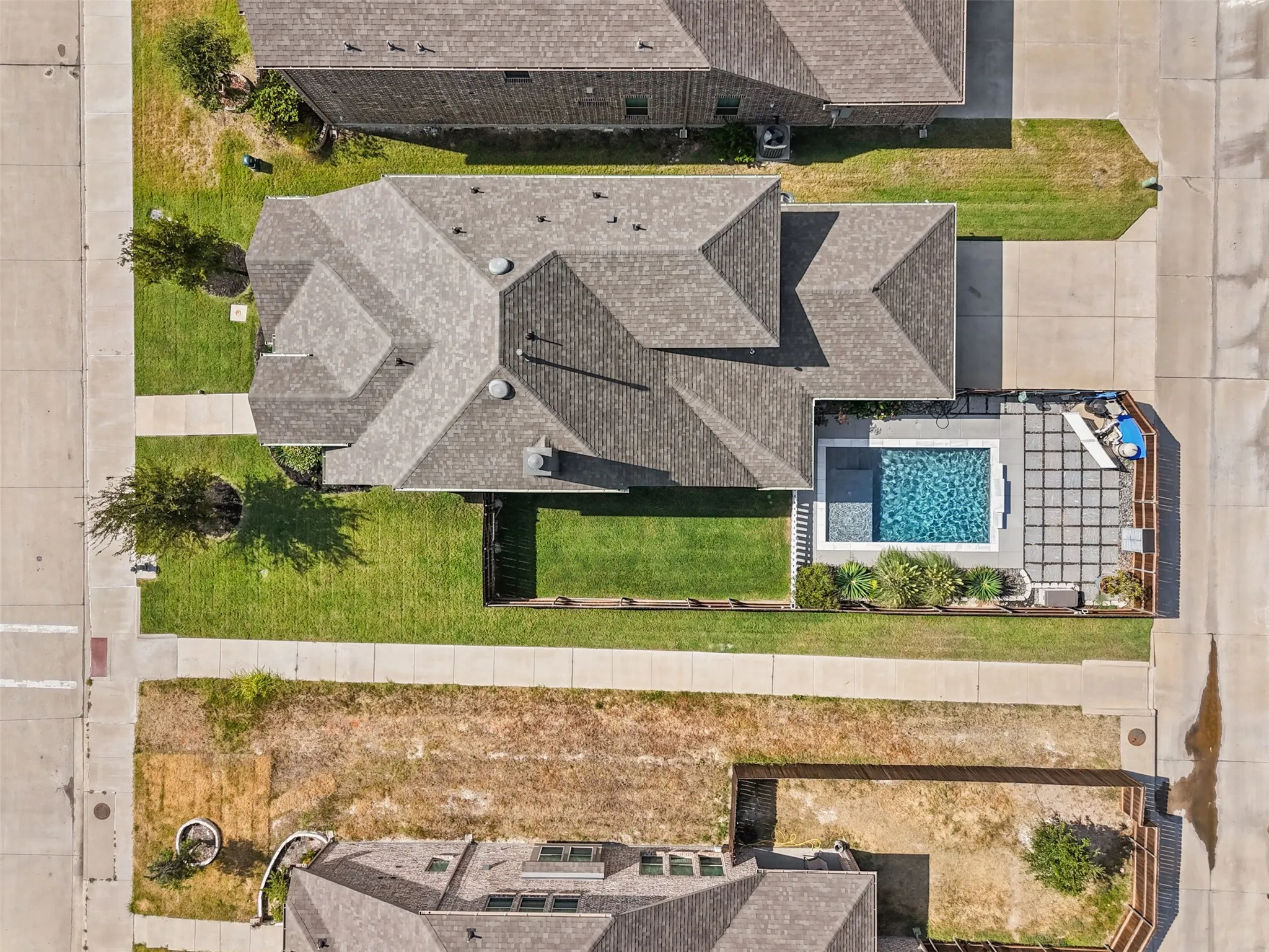 Rectangular swimming pool with integrated spa and surrounding paver patio