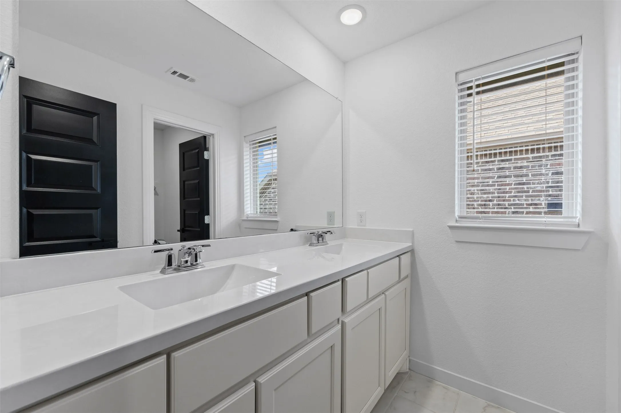 2nd Story Dual vanity with integrated sinks, chrome fixtures, a full-width mirror, and under-counter storage