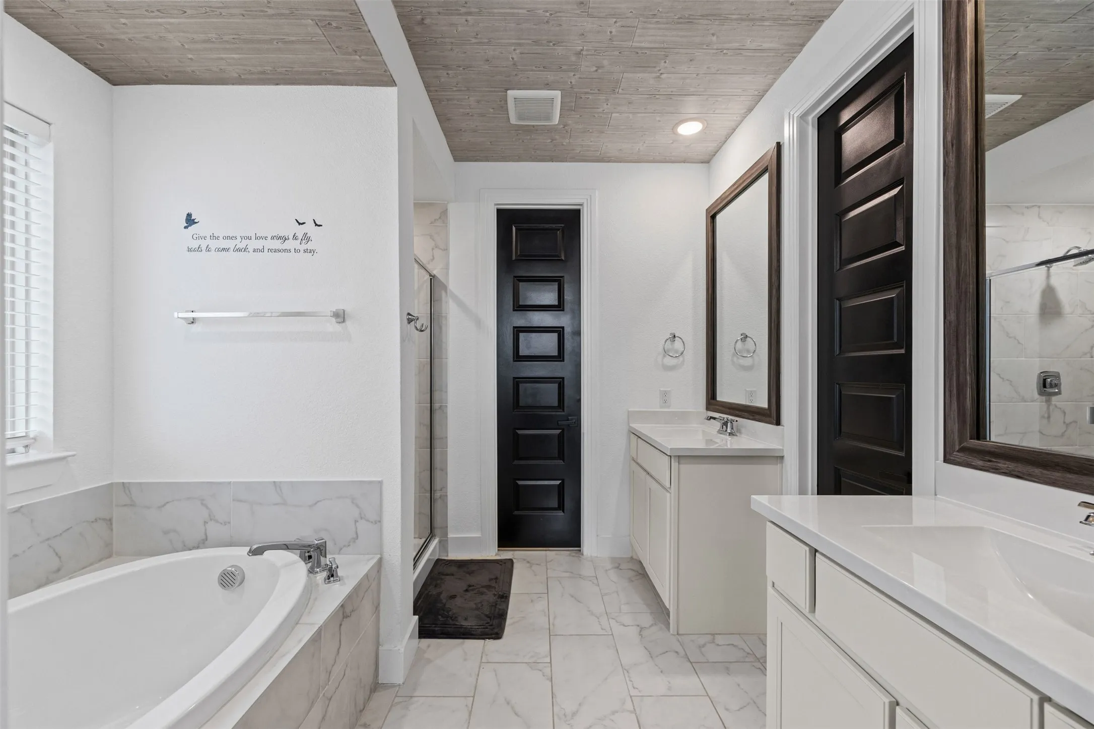 Dual vanity with undermount sinks, a built-in soaking tub, a glass-enclosed shower, and wood-finish ceiling details