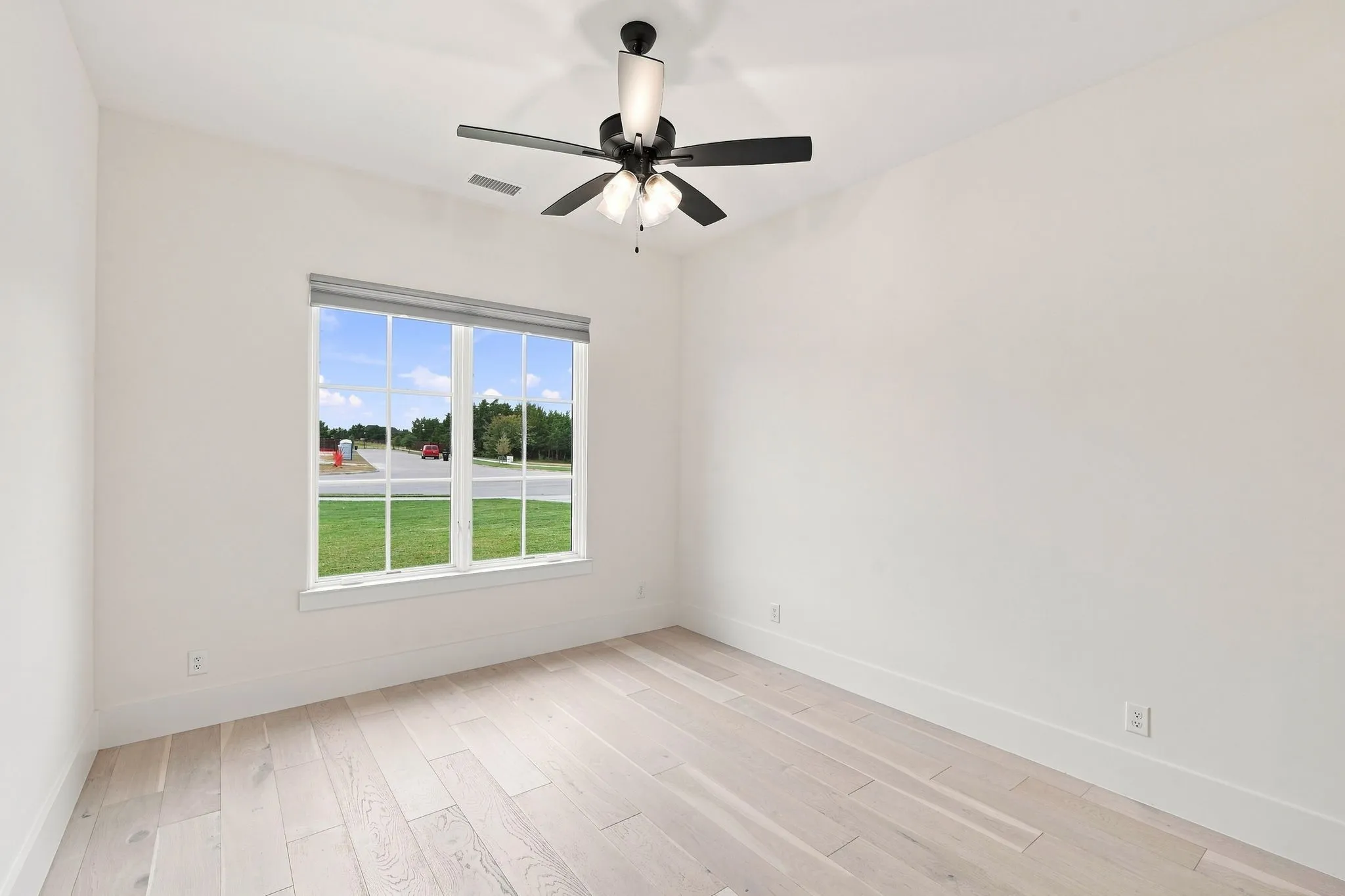 Bright corner bedroom flooded with natural light through expansive dual-pane windows overlooking manicured grounds