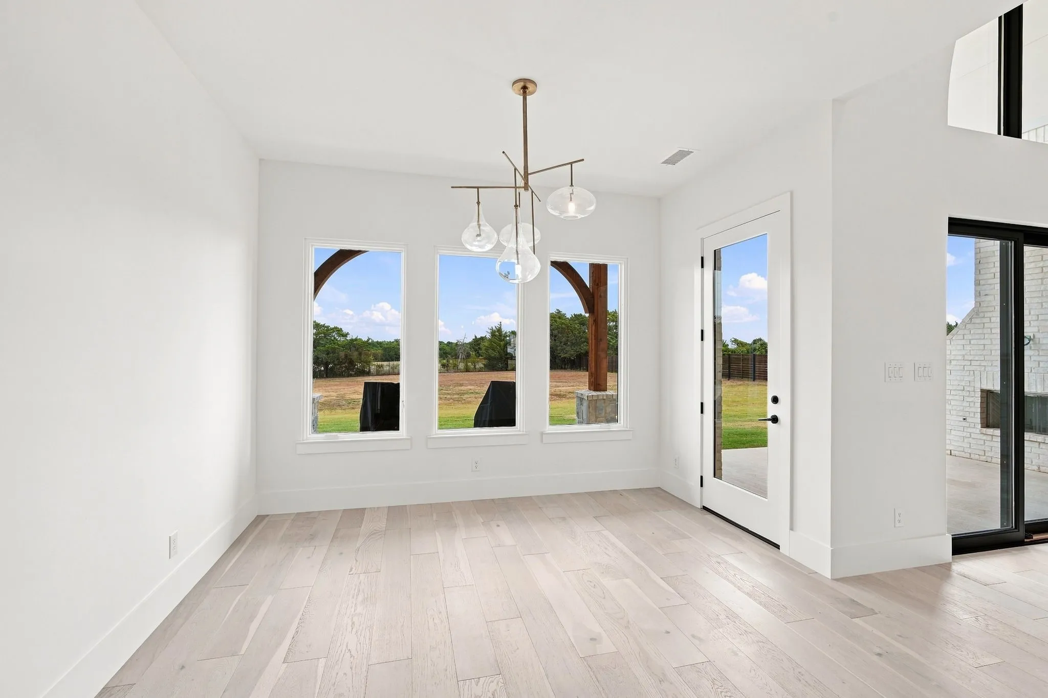 Bright, open living space flooded with natural light through expansive multi-pane windows and glass door