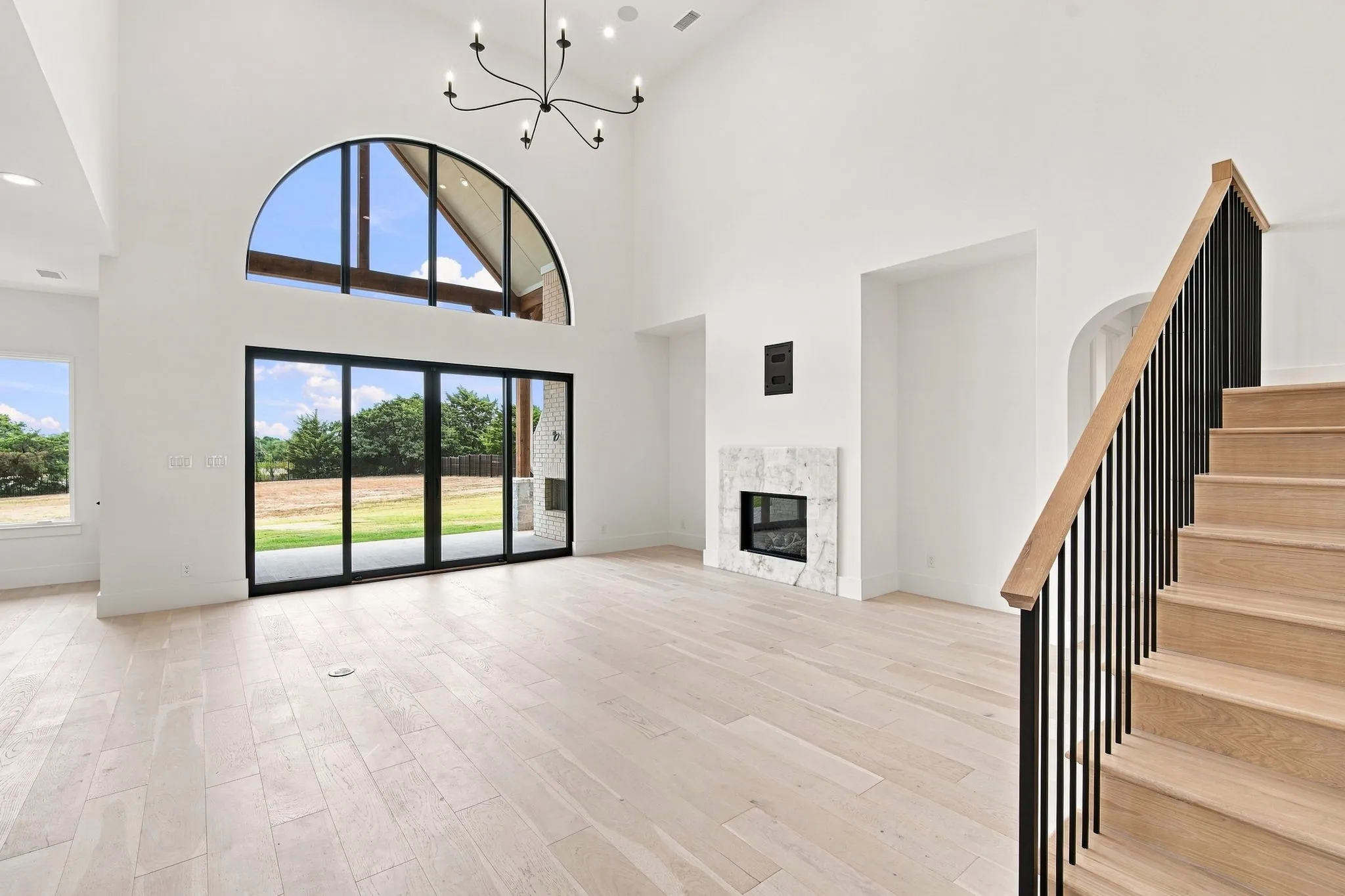 Bright, open great room with soaring ceilings and arched transom window flooding the space with natural light