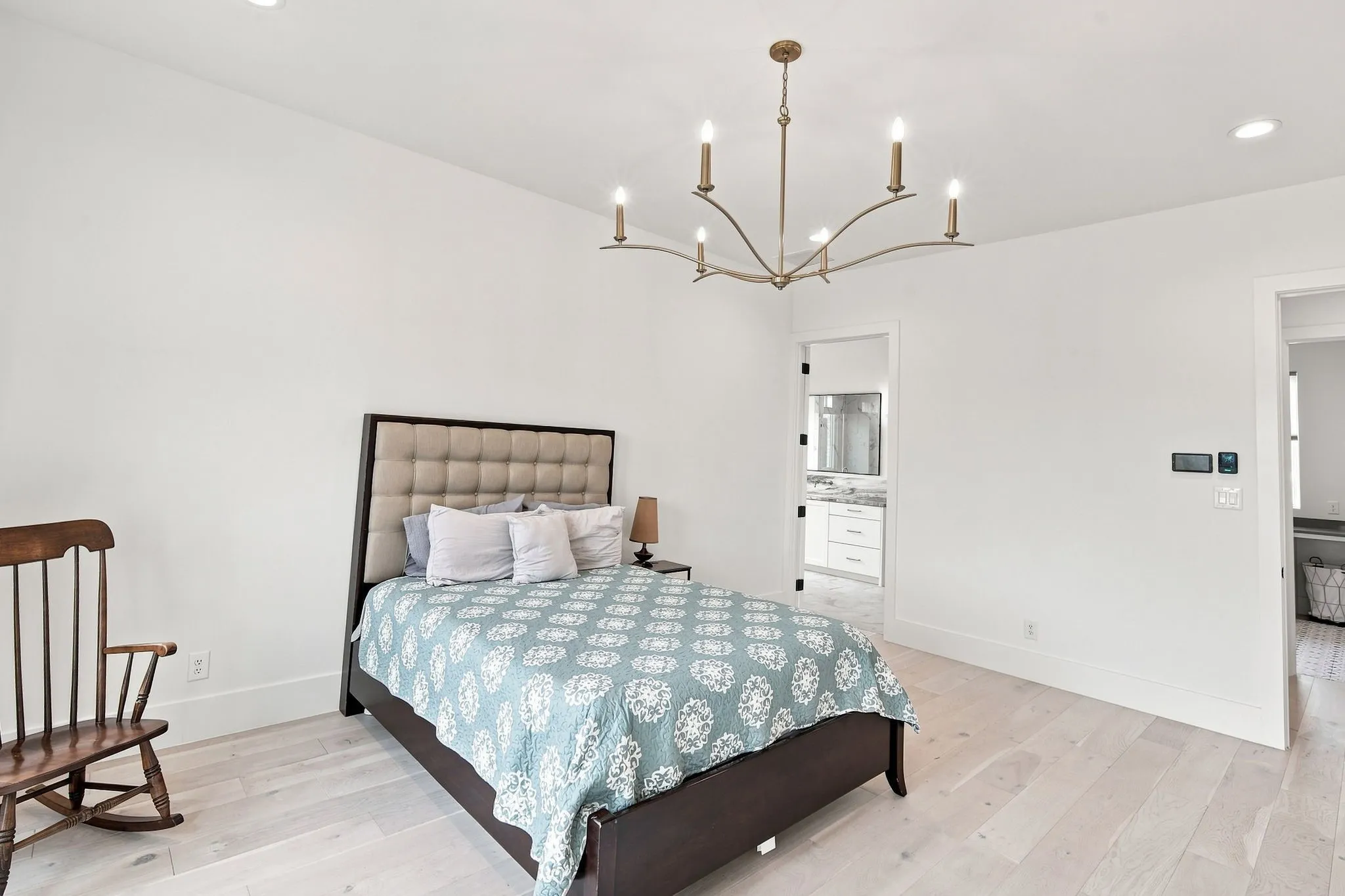 Spacious primary bedroom with light wood-finish flooring, soft neutral wall finishes, and abundant natural light