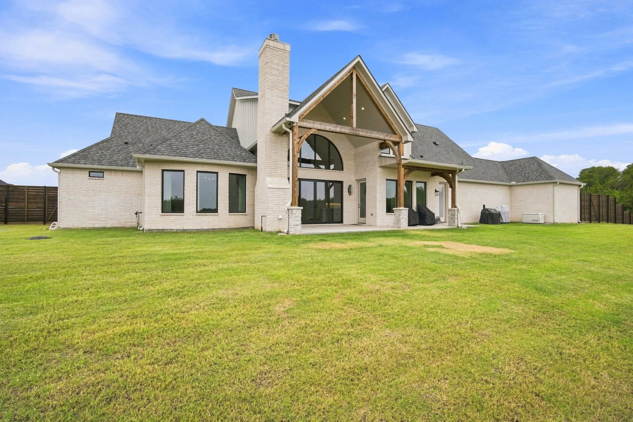 Stunning contemporary home showcasing a cream and stone exterior with peaked gable rooflines, tall chimney, and multi-pane windows