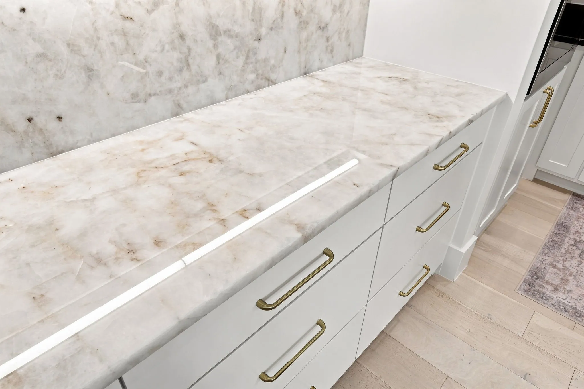 Elegant kitchen cabinetry featuring crisp white painted finishes with brushed gold hardware and multiple storage drawers