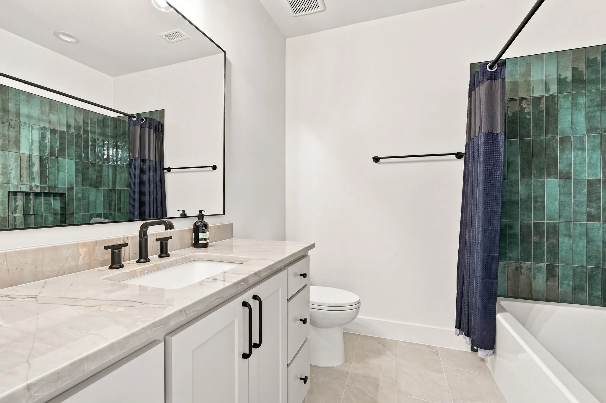 Spa-inspired primary bathroom featuring a marble-topped vanity with dual sink configuration, matte black hardware, and an expansive framed mirror