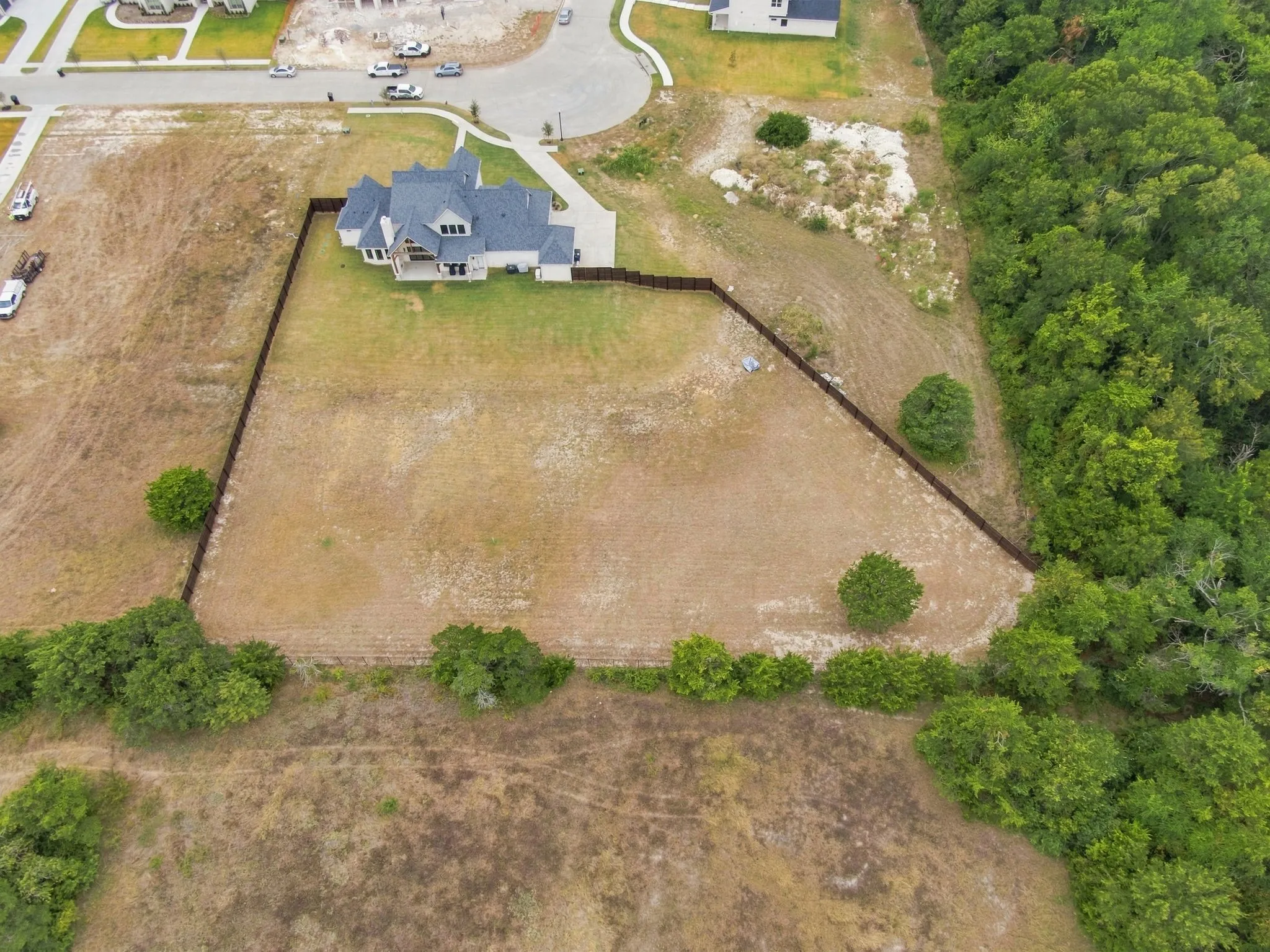 Expansive residential lot featuring a two-story home with dark architectural shingles, situated on approximately 1+ acre of cleared land