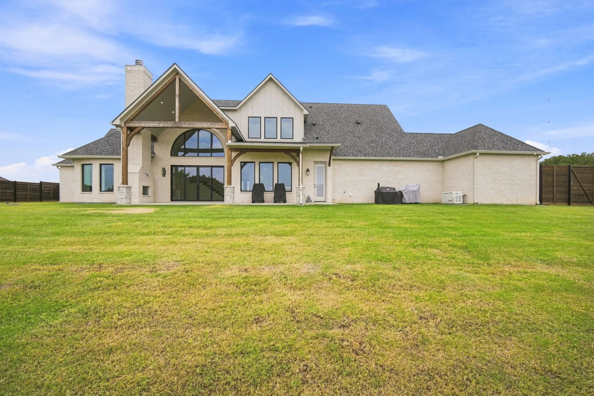 Stately residence featuring a cream-toned exterior with pitched gable rooflines, arched entryway, and multi-pane windows