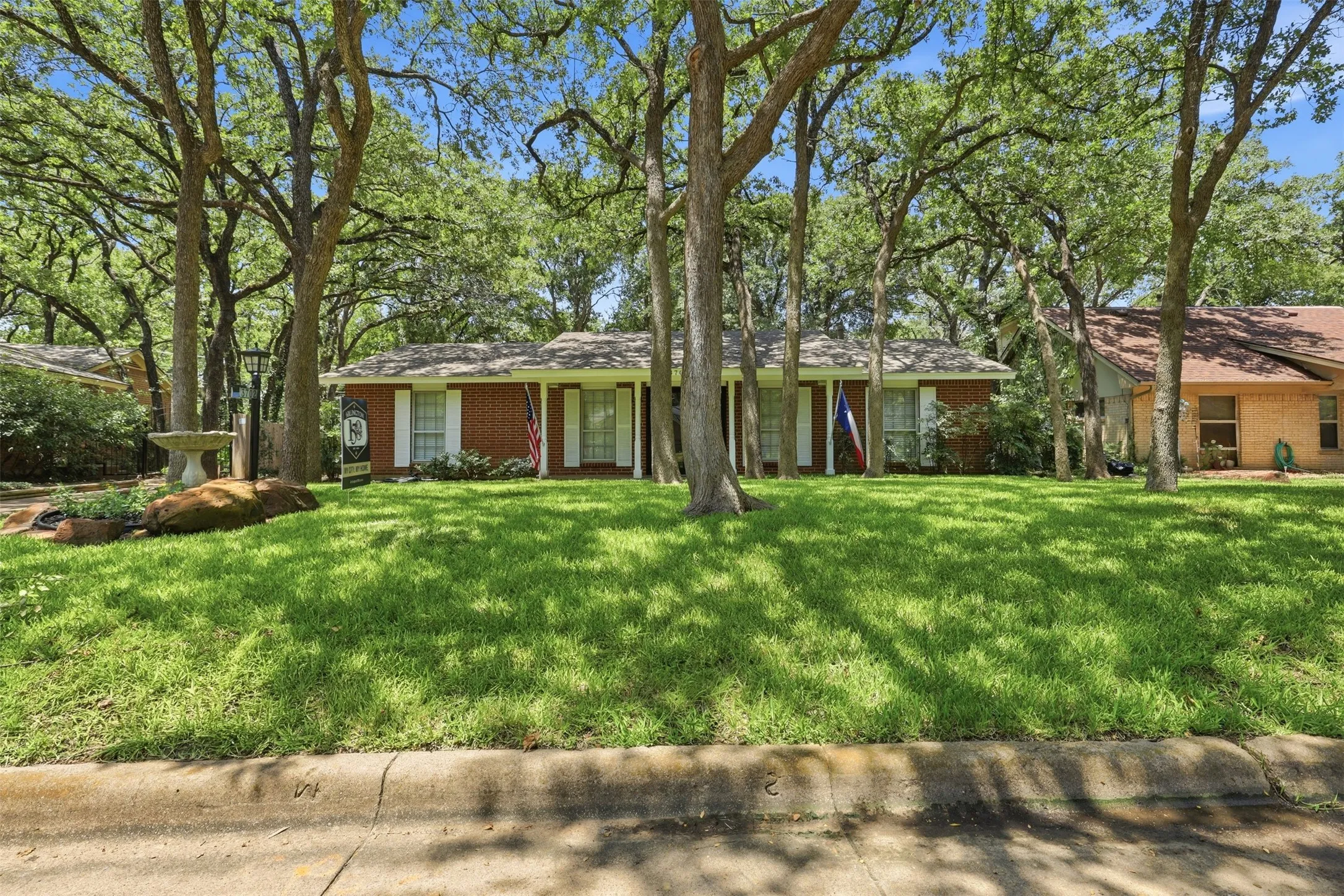 Single-story Arlington home with attractive curb appeal, a heavily treed lot, green lawn, and an established Woodland West neighborhood setting