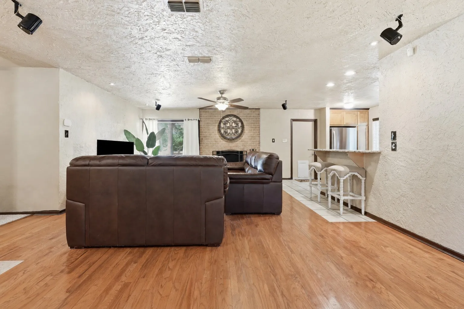 Living room with wood flooring, ceiling fan, generous seating space, and an open flow toward the kitchen and dining areas