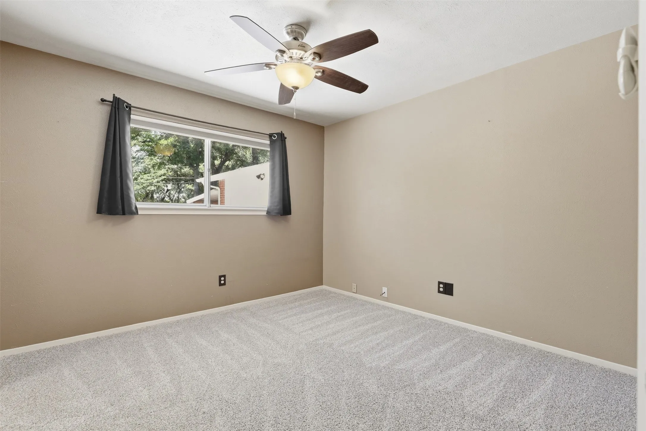 Primary bedroom with new carpet installed July 2026, ceiling fan, natural light, and convenient access to the bathroom and storage area