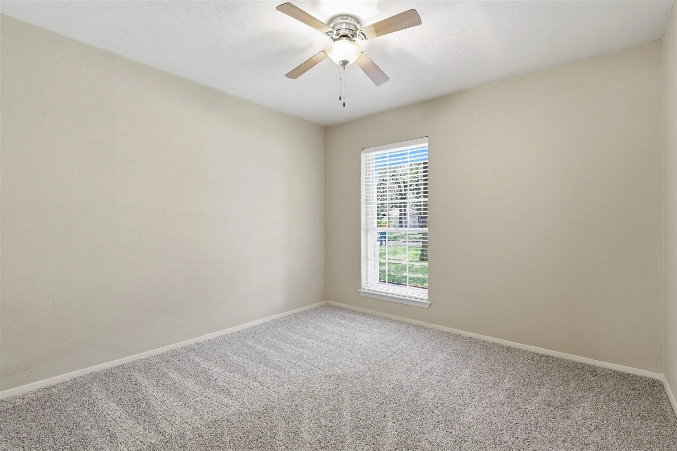 Bedroom #2 - Bright secondary bedroom with new carpet installed July 2026, ceiling fan, neutral paint, and natural light in this Arlington, TX 76013 home