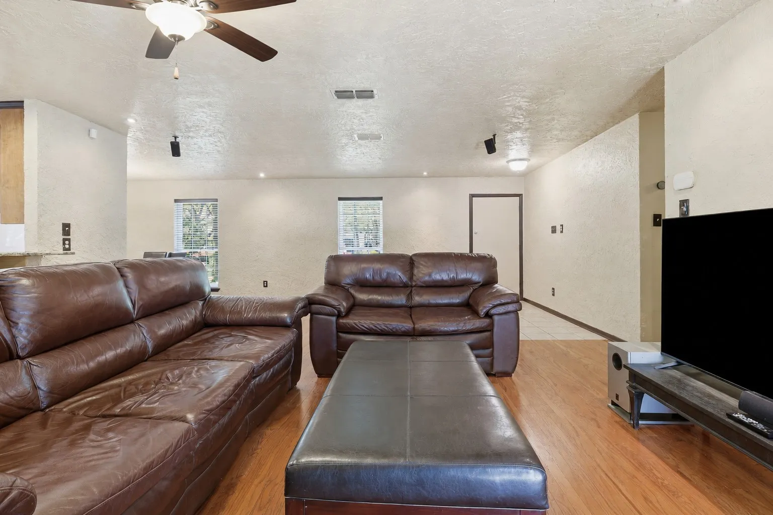 Large living area with wood floors, multiple windows, recessed lighting, and flexible space for entertaining or everyday living